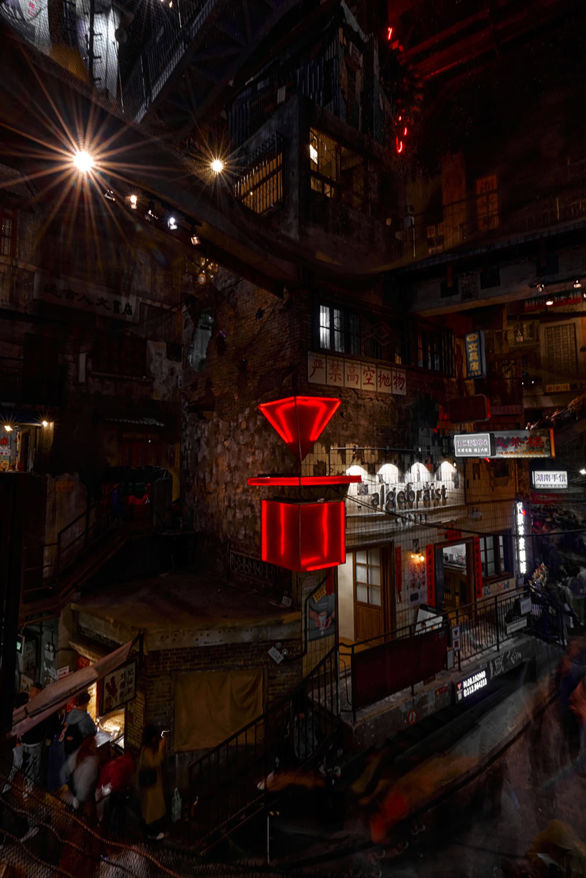 A nighttime city street scene with a red box on display in front of a building, blending photo and architectural render elements