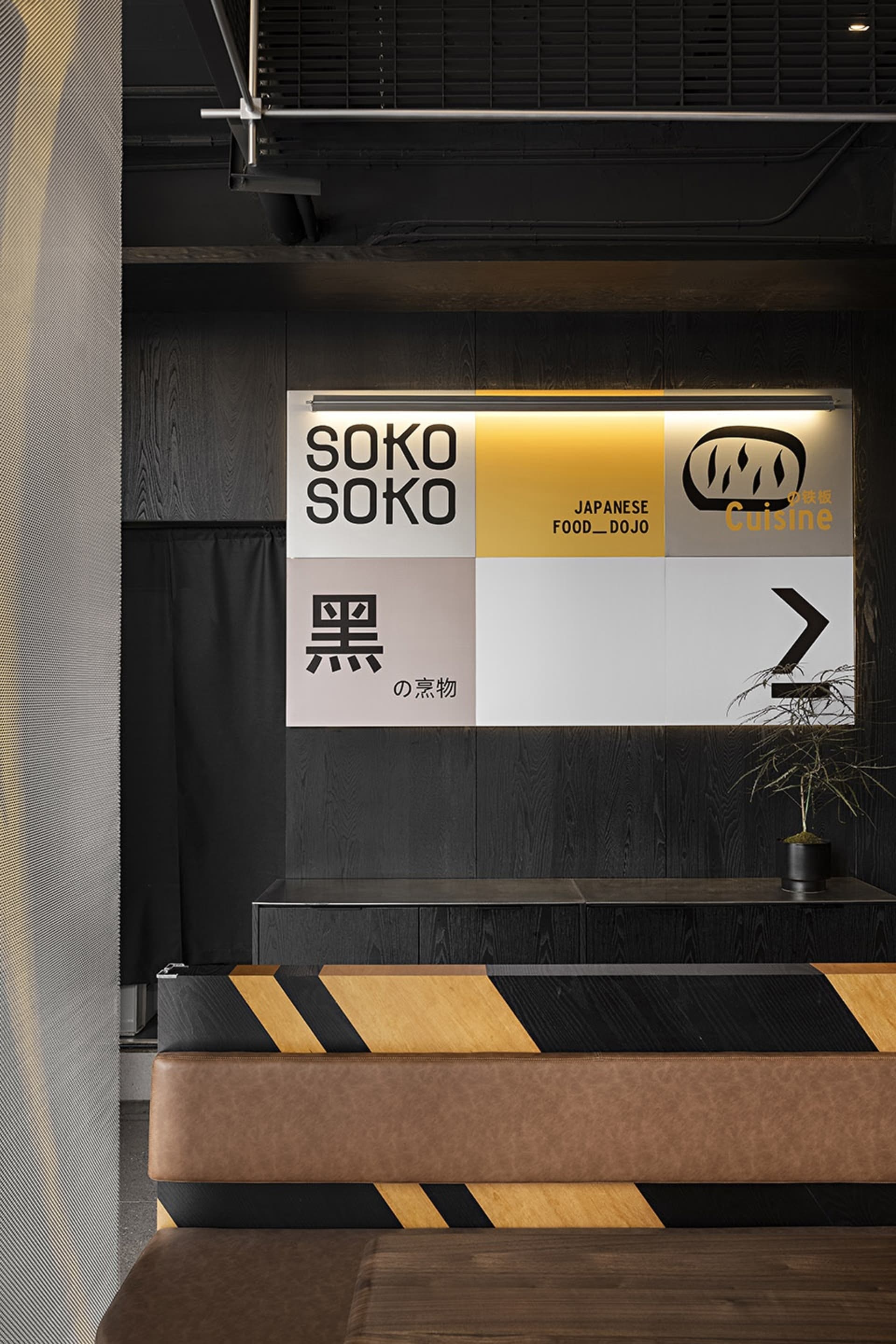 Cozy Asian restaurant with a wooden countertop, black and yellow striped wall, and signs on display