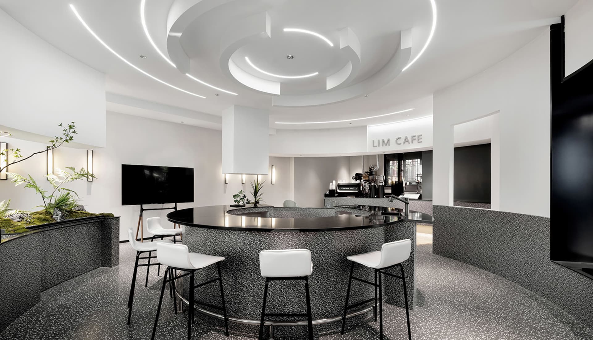 A cozy cafe with a circular bar surrounded by chairs and tables, featuring potted plants and an inviting atmosphere