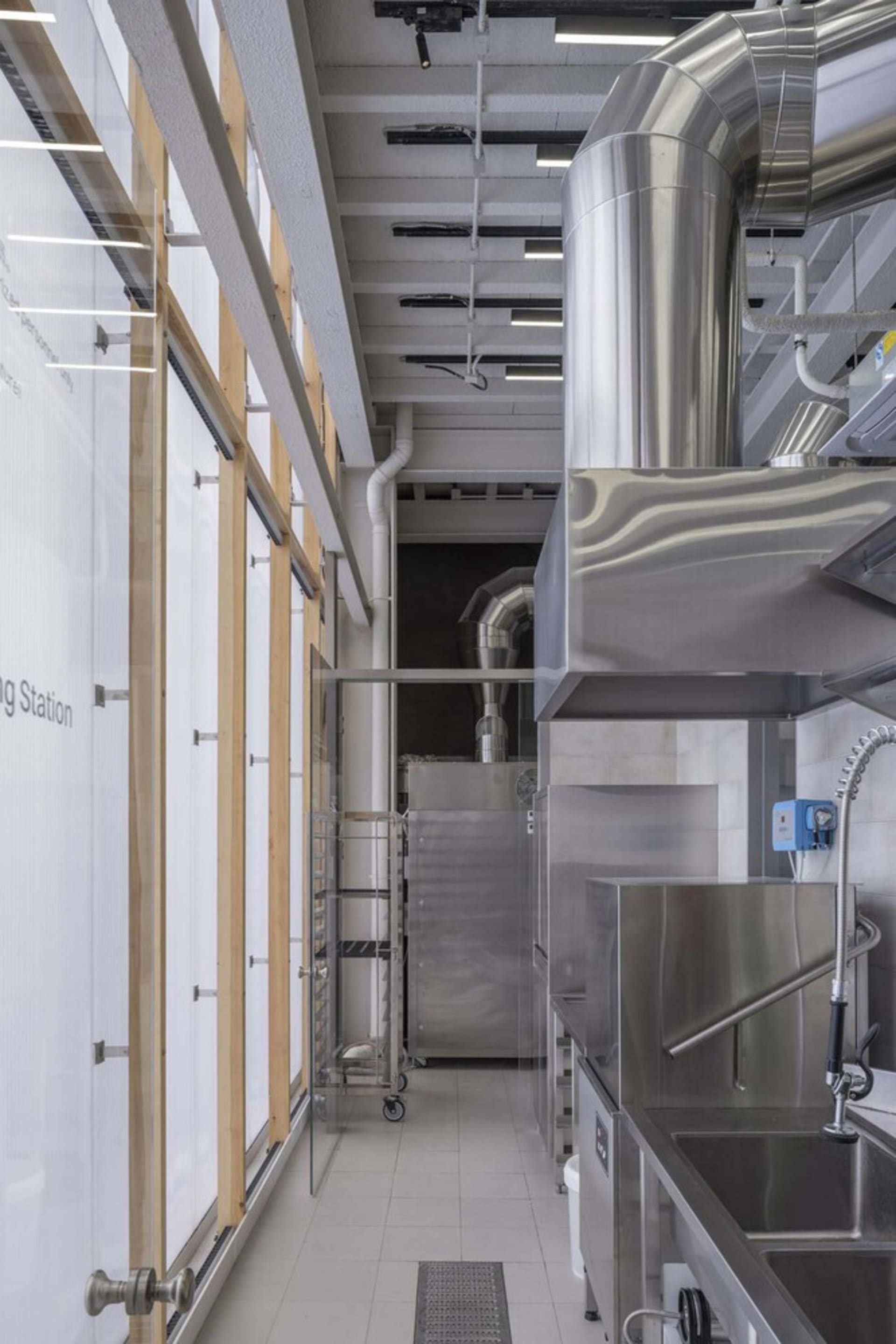 Industrial kitchen with stainless steel appliances and fixtures, featuring multiple ovens and sinks in a functional and professional environment