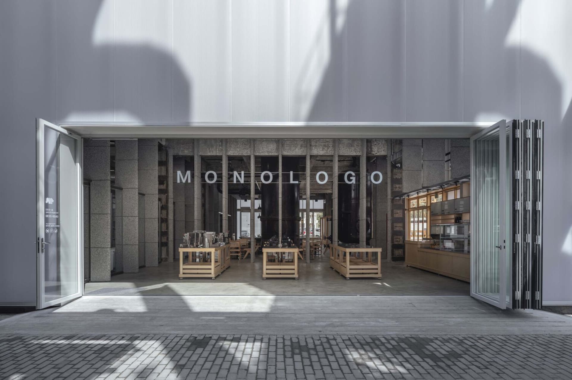 A cozy coffee shop interior with a large display window showcasing cups, bowls, and bottles, surrounded by chairs for customers to sit and enjoy their beverages