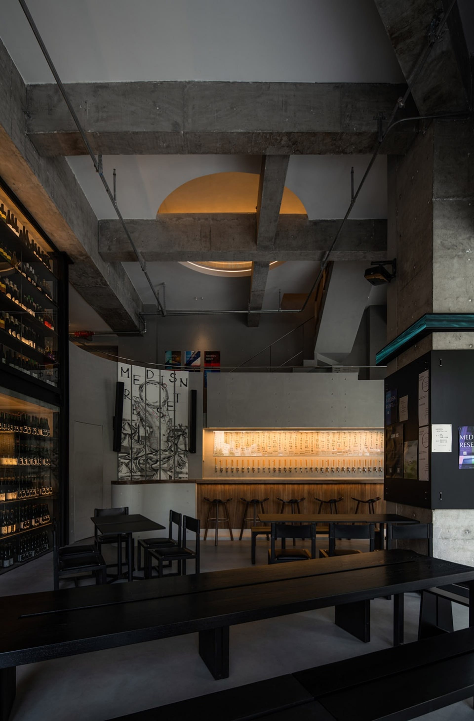 A well-lit dining area with a large wooden table and chairs, surrounded by bottles and a modern atmosphere