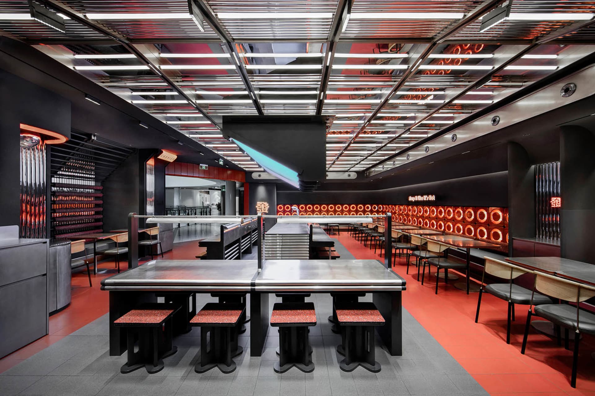 Industrial kitchen dining space with a large dining table, multiple chairs, and benches, featuring a functional and practical atmosphere