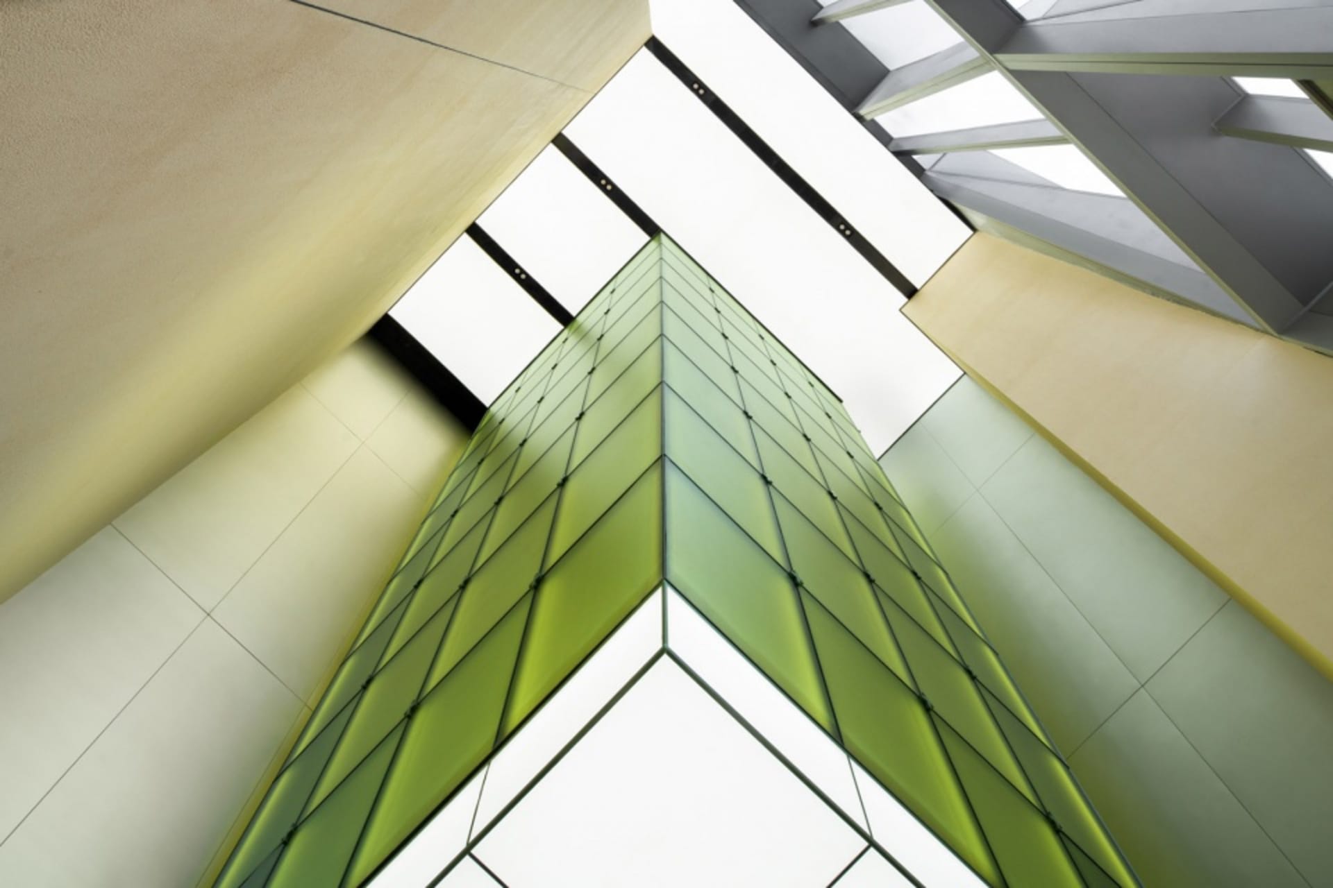 Tall modern building with green glass walls, a striking contrast to its surroundings, conveying a sense of functionality and aesthetics