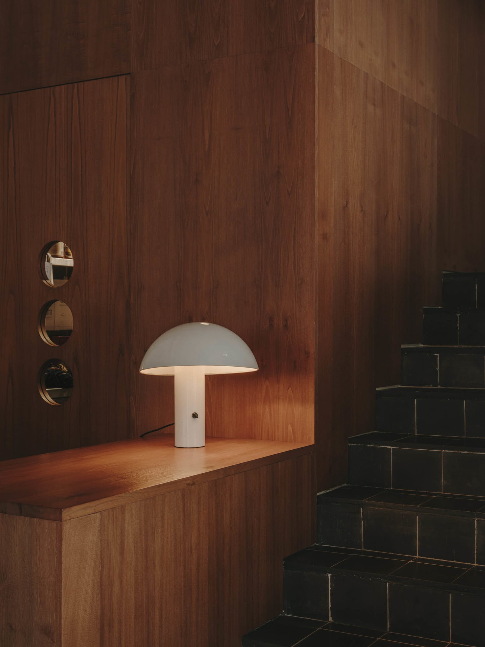 A warm and inviting interior space with a wooden table and a unique globe-shaped lamp, surrounded by cozy wooden elements