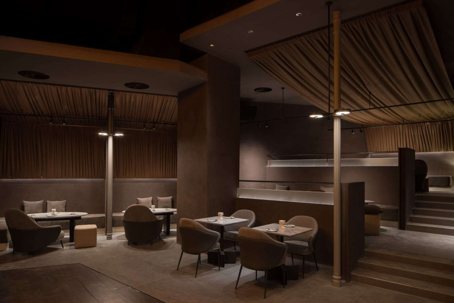A restaurant interior with dining tables, chairs, and couches arranged to create a cozy atmosphere for guests to enjoy their meals