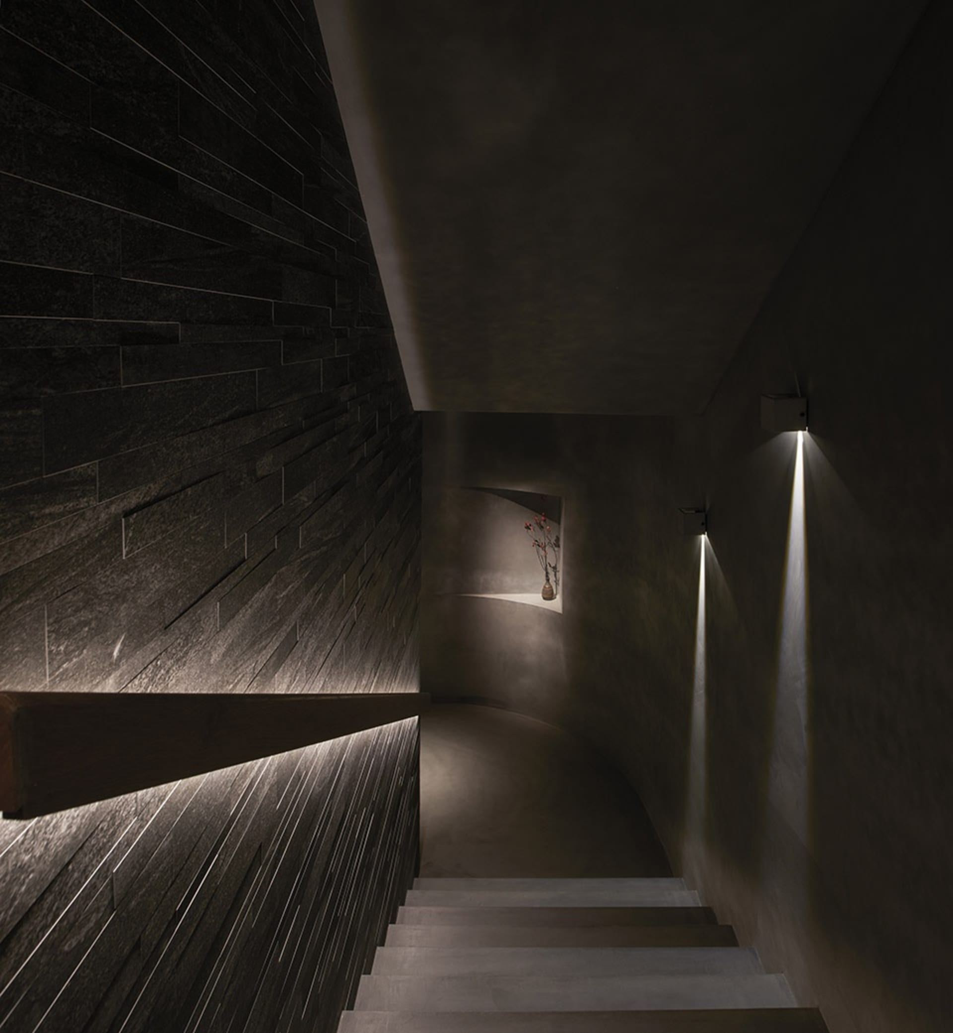 A darkened room with a stone staircase featuring two sets of steps, one on each side of the room