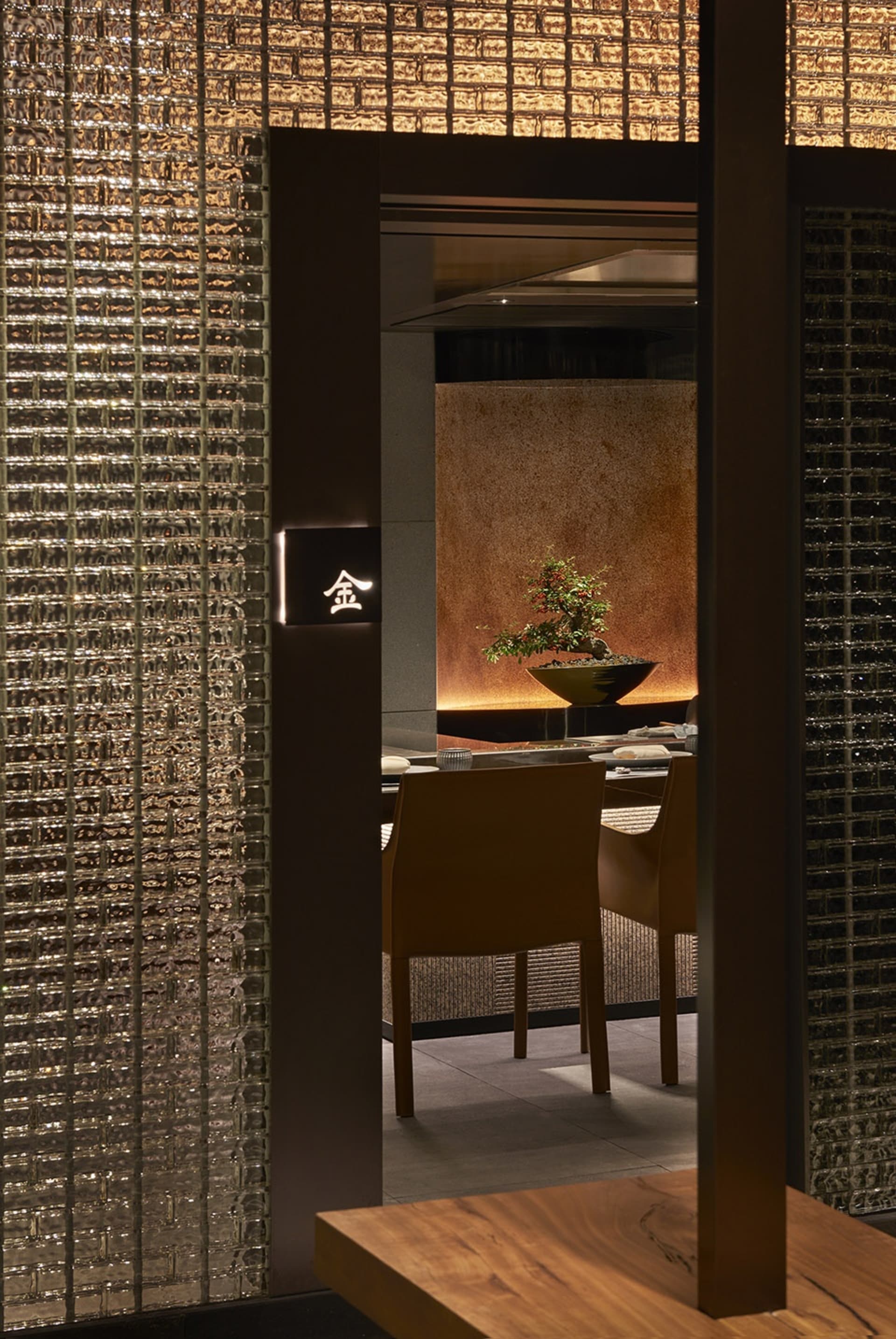 Warm and inviting Asian restaurant with a wooden interior, two chairs, a potted plant, and tiled walls
