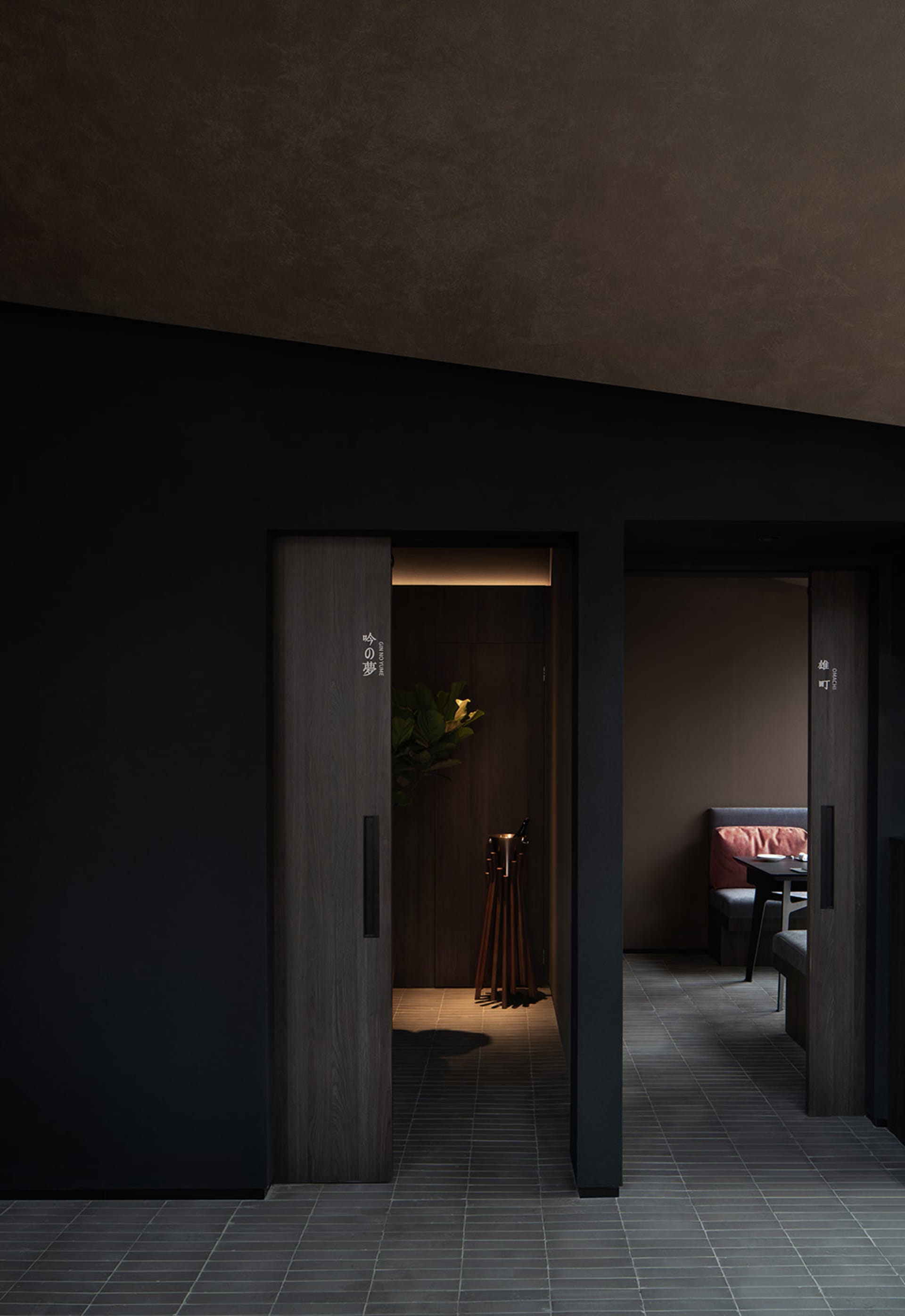 A well-organized hallway with two doors, a potted plant, and signs on the walls