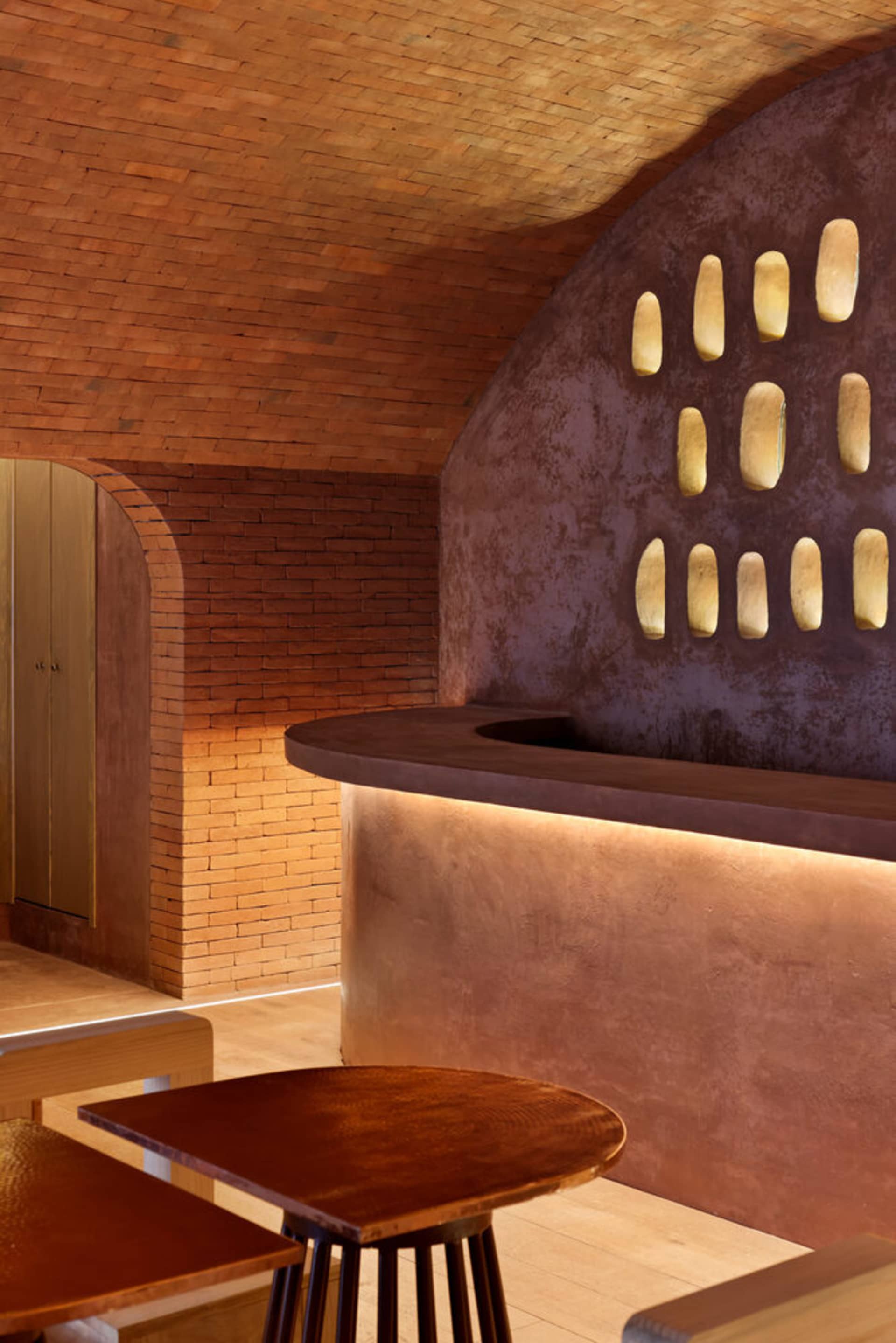 Warm and inviting restaurant interior with a brick wall, wooden tables, and a bench, creating a cozy atmosphere