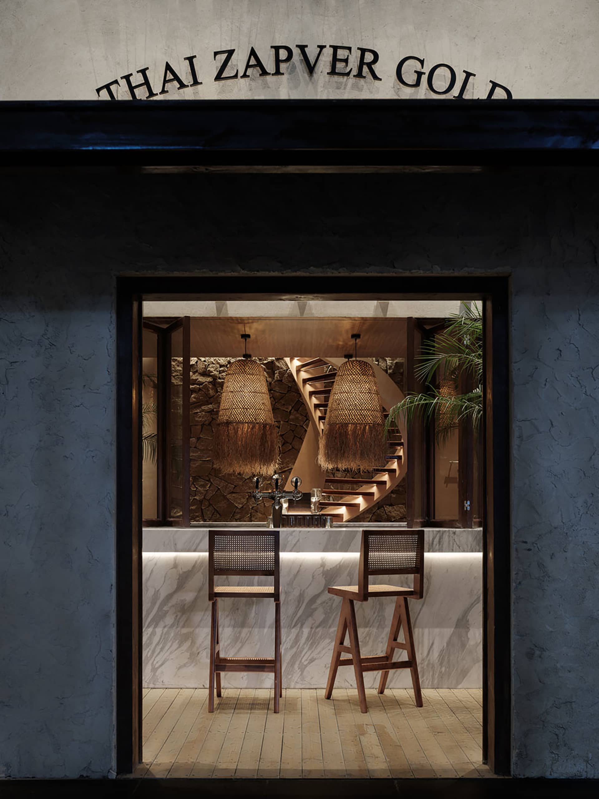 Modern kitchen with wooden bar stools and marble countertop, featuring a sink and two chairs, with a sophisticated atmosphere created by the use of wood and marble