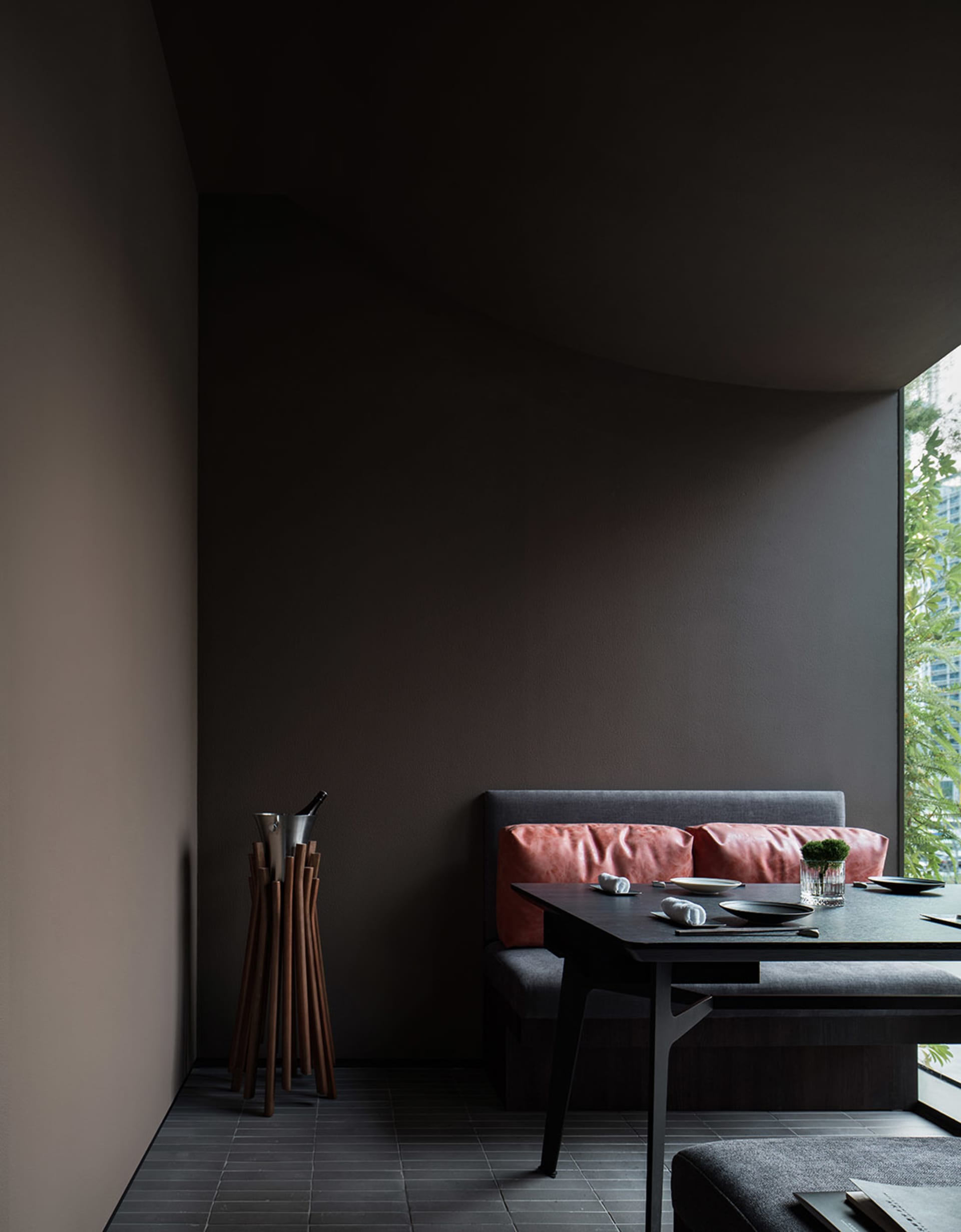 A darkly colored dining room with a table and chairs, two couches, and a vase adding to the cozy ambiance