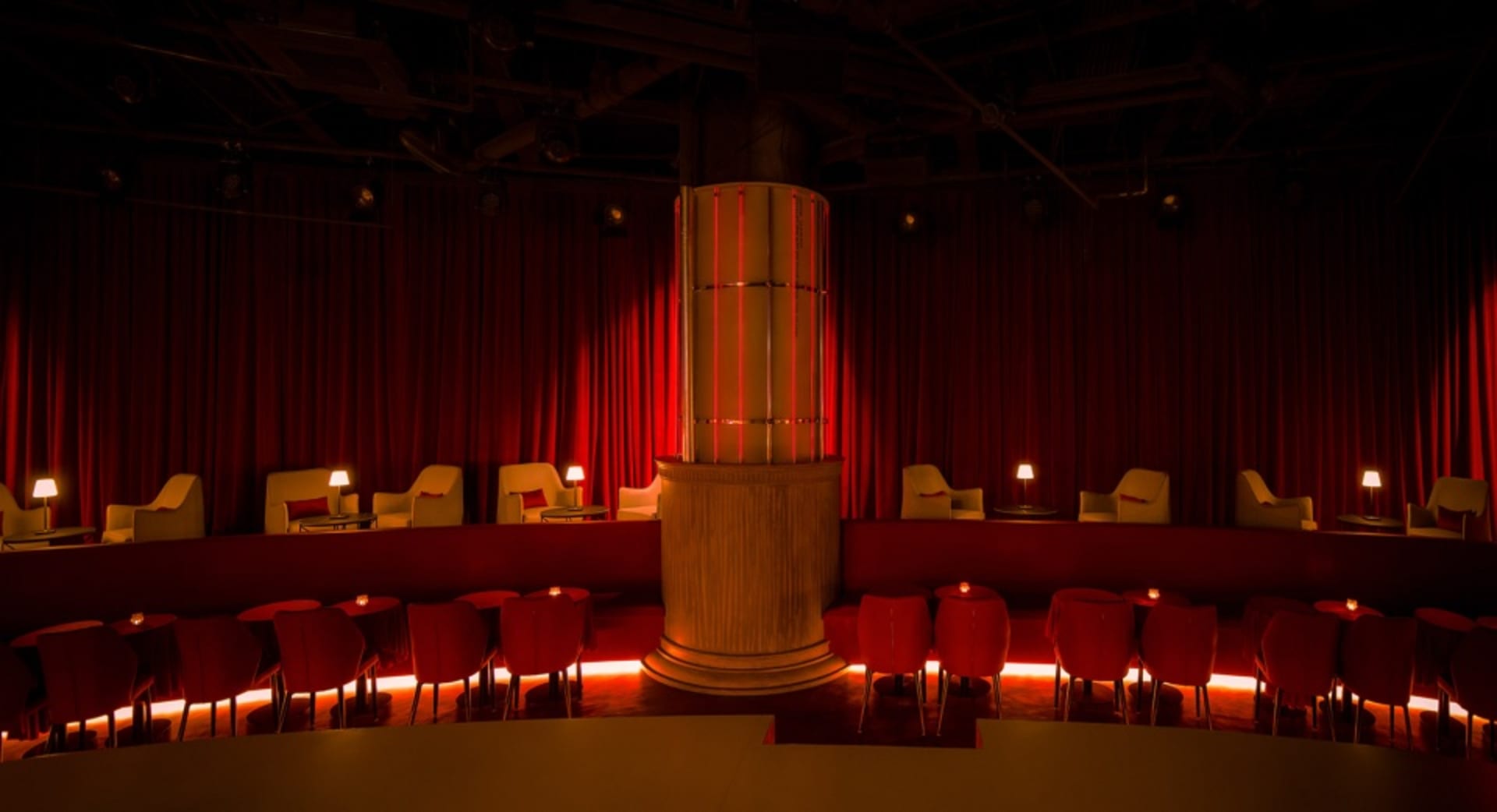 Warm and inviting restaurant interior with red velvet walls, curtains, and chairs around dining tables