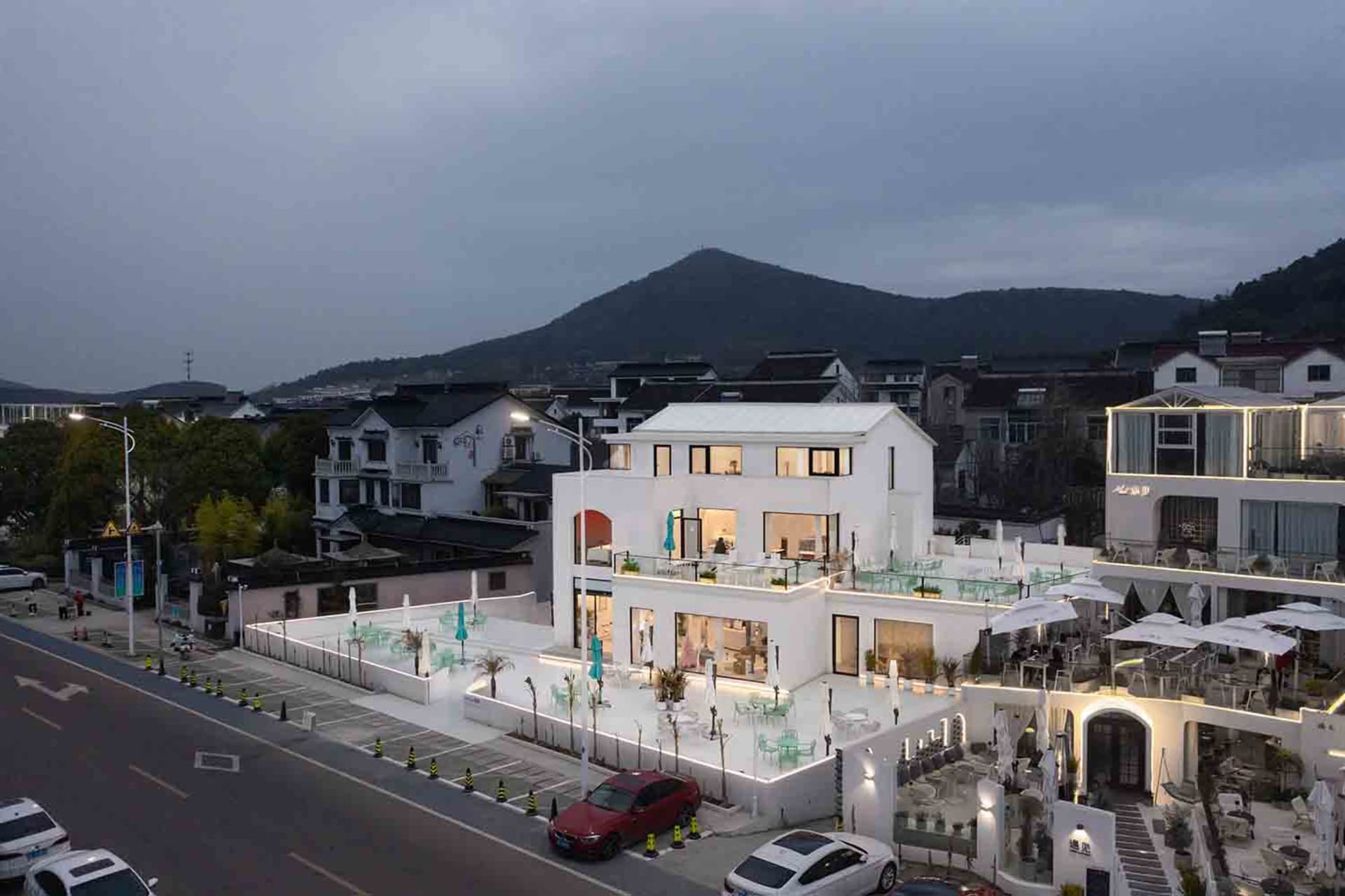 A modern luxury building with multiple levels, a rooftop terrace, and a mix of concrete, glass, and wood materials