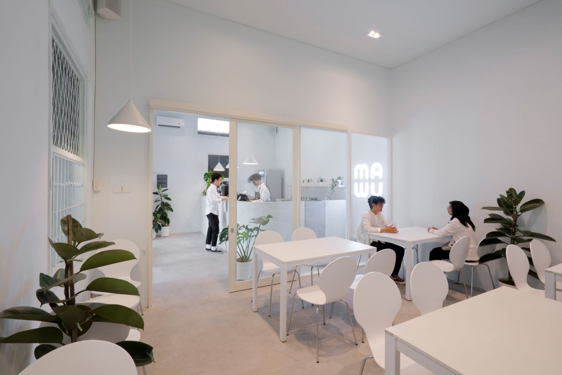 A casual restaurant with white chairs and tables, people sitting and enjoying meals in a welcoming atmosphere