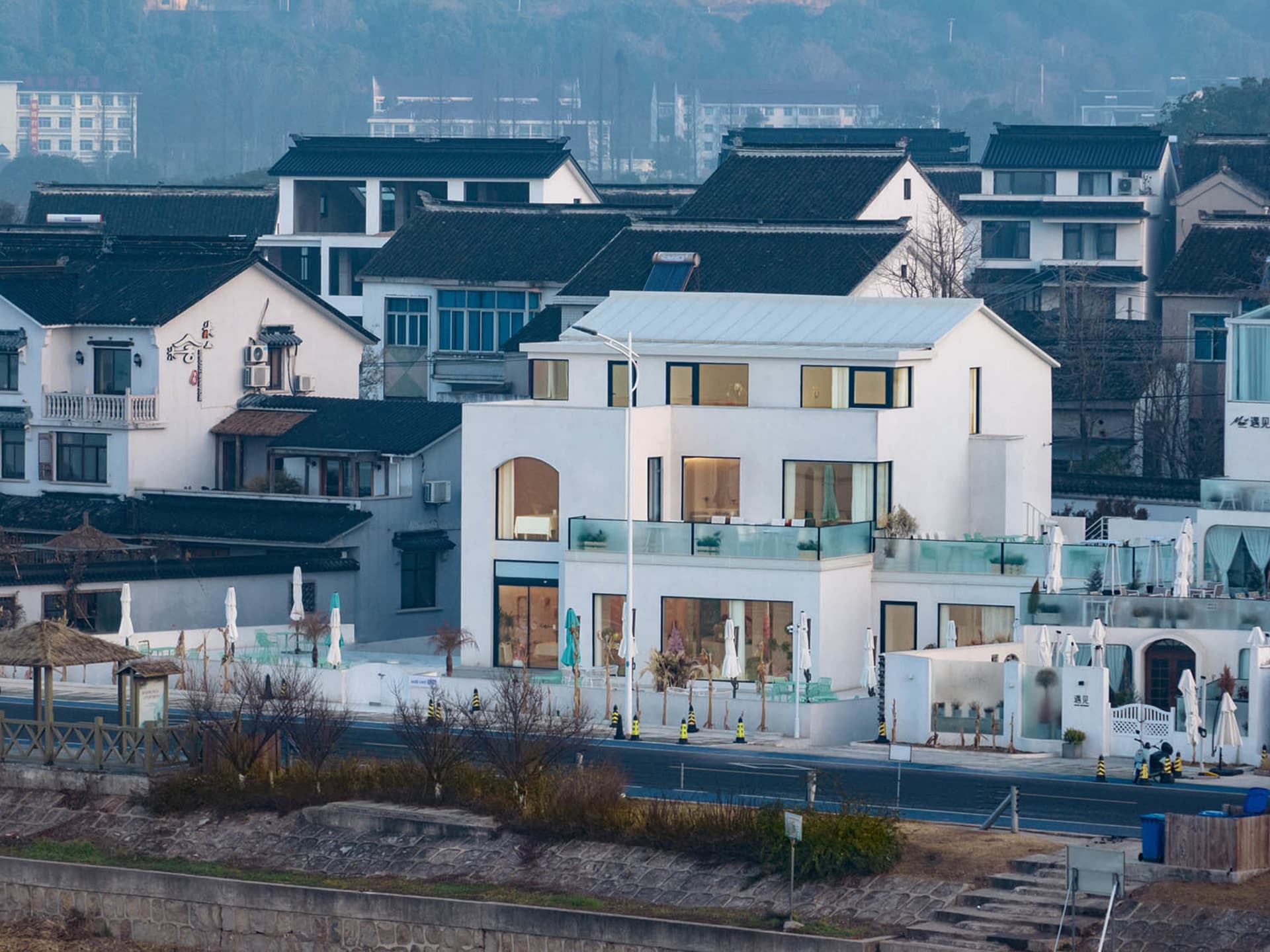 一座多層現代建築，配有陽台與窗戶，位於都市環境中，點綴盆栽與綠意