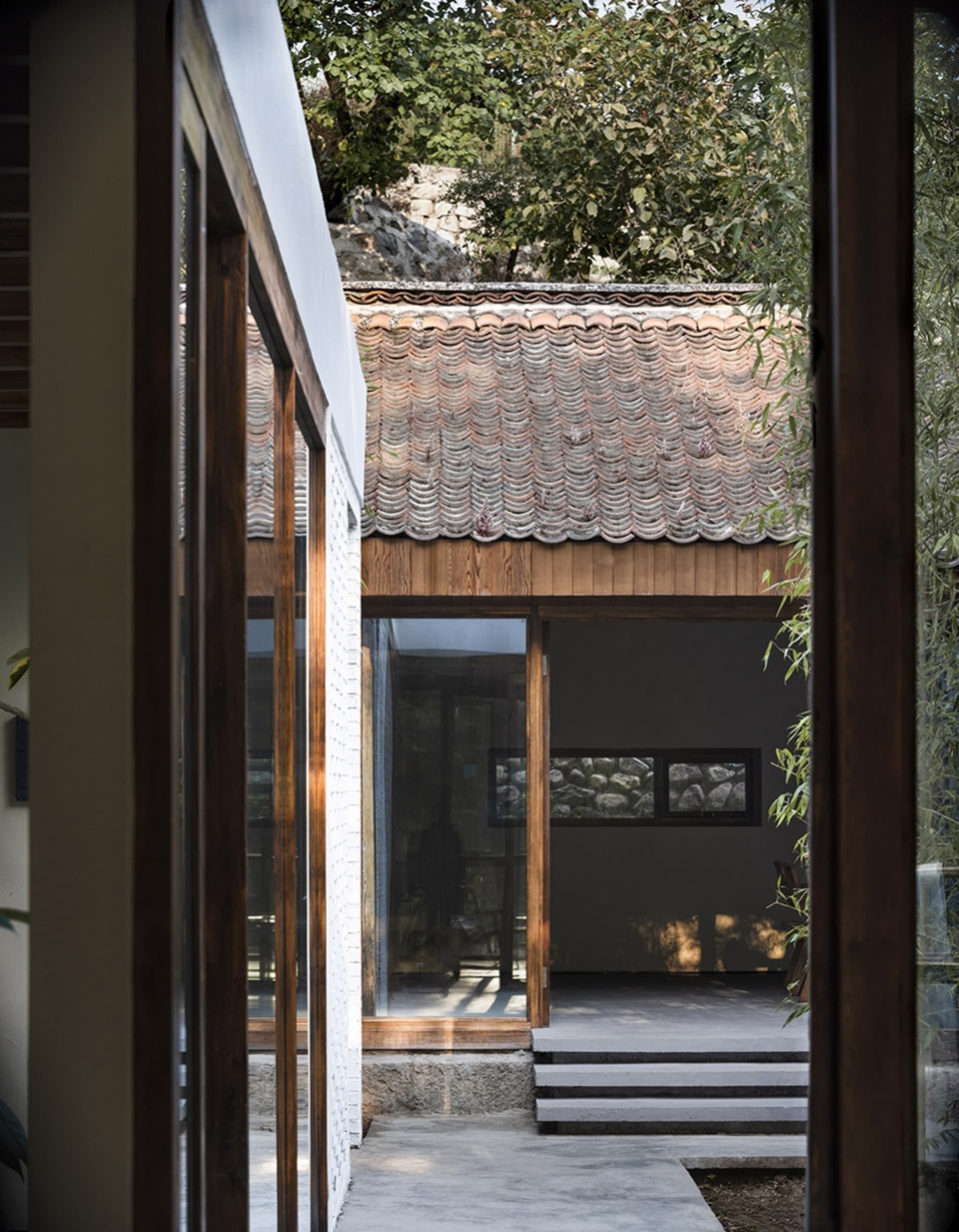 Open living area with wooden walls, floors, and two windows providing natural light