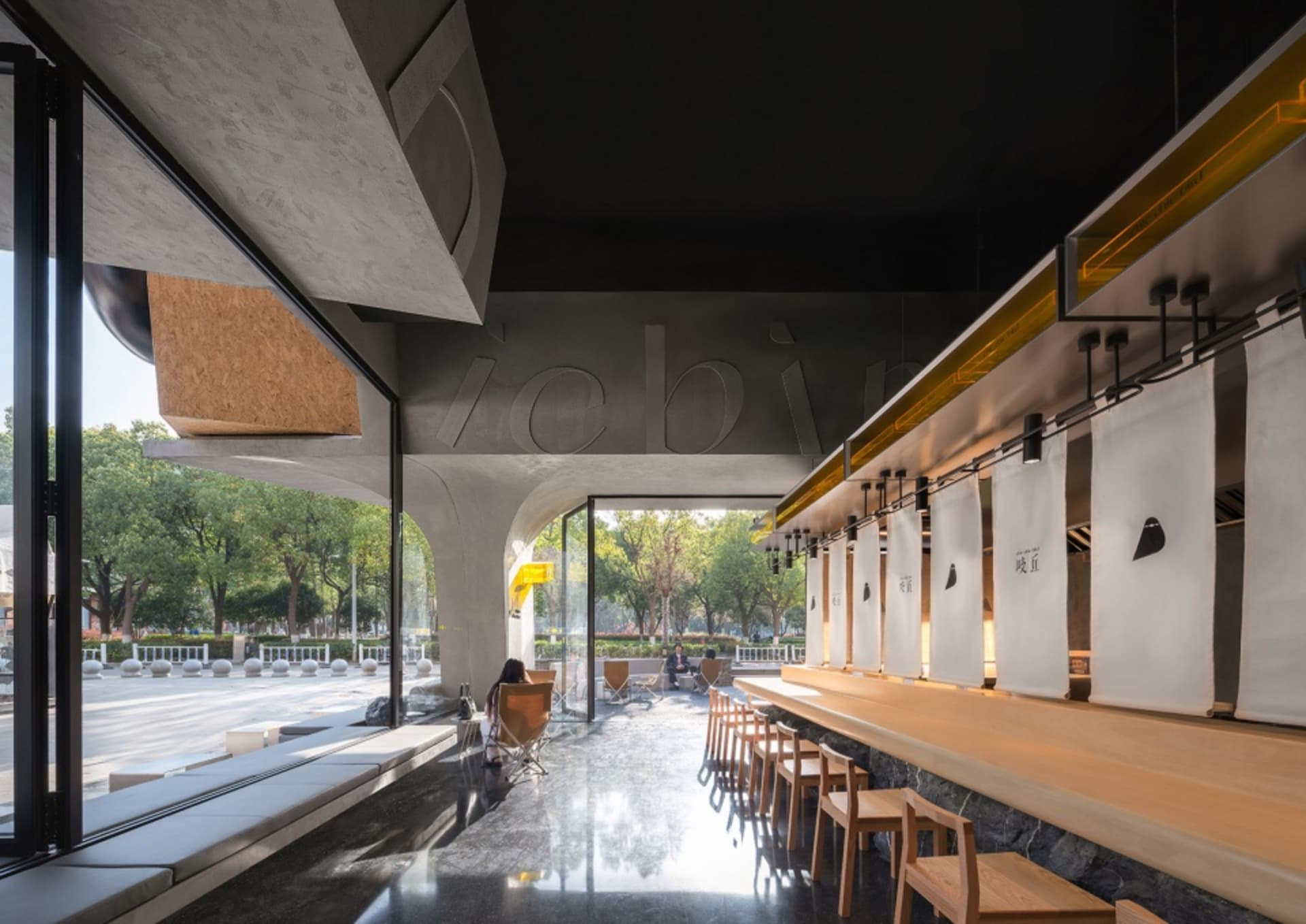 A casual restaurant with a large dining table surrounded by chairs, warm lighting, and a mix of wood and metal elements