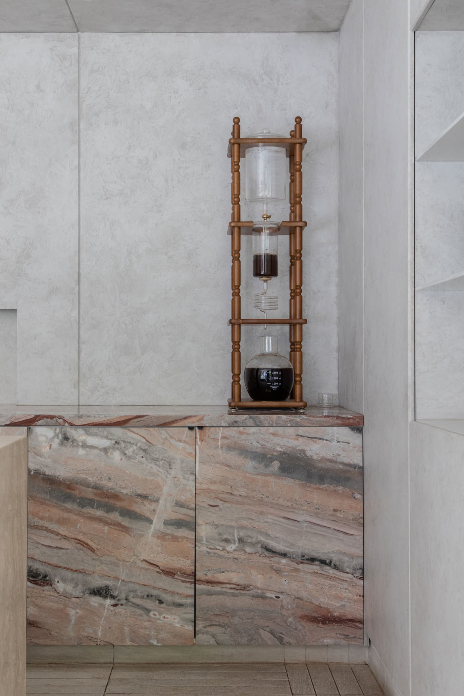 Elegant kitchen with a marble countertop, wooden cabinetry, and decorative vases, set for dining or entertaining