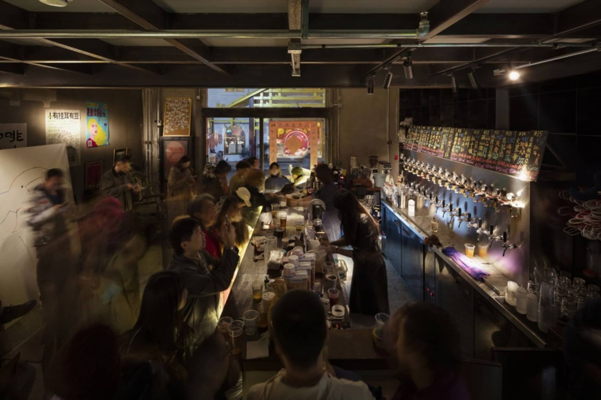 A lively bar scene with people gathered around a counter, enjoying drinks and socializing, surrounded by bottles, cups, and bowls, with a casual and relaxed atmosphere