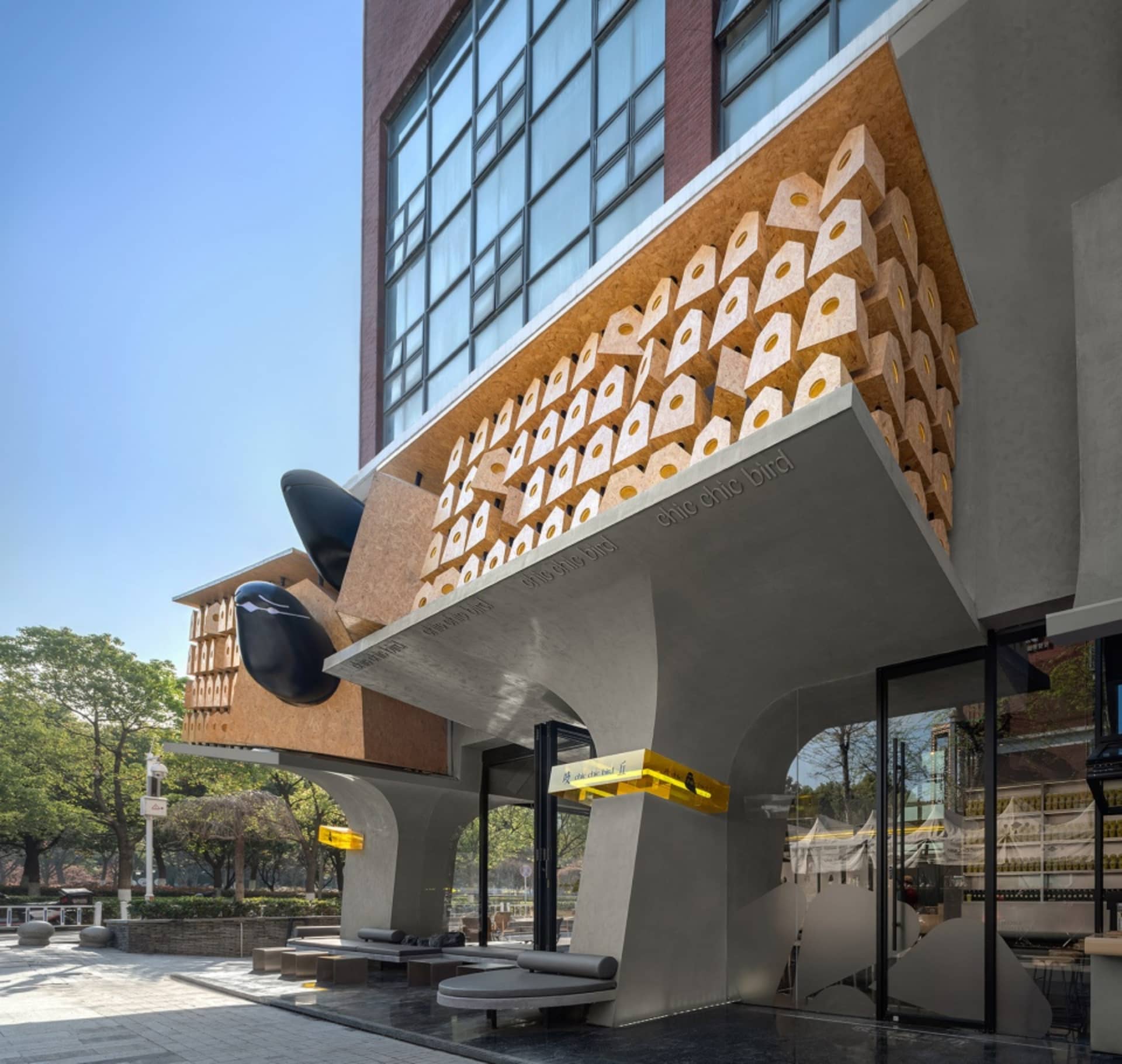 A modern building with a unique black geometric feature, concrete structure, and multiple windows, set against a neutral background