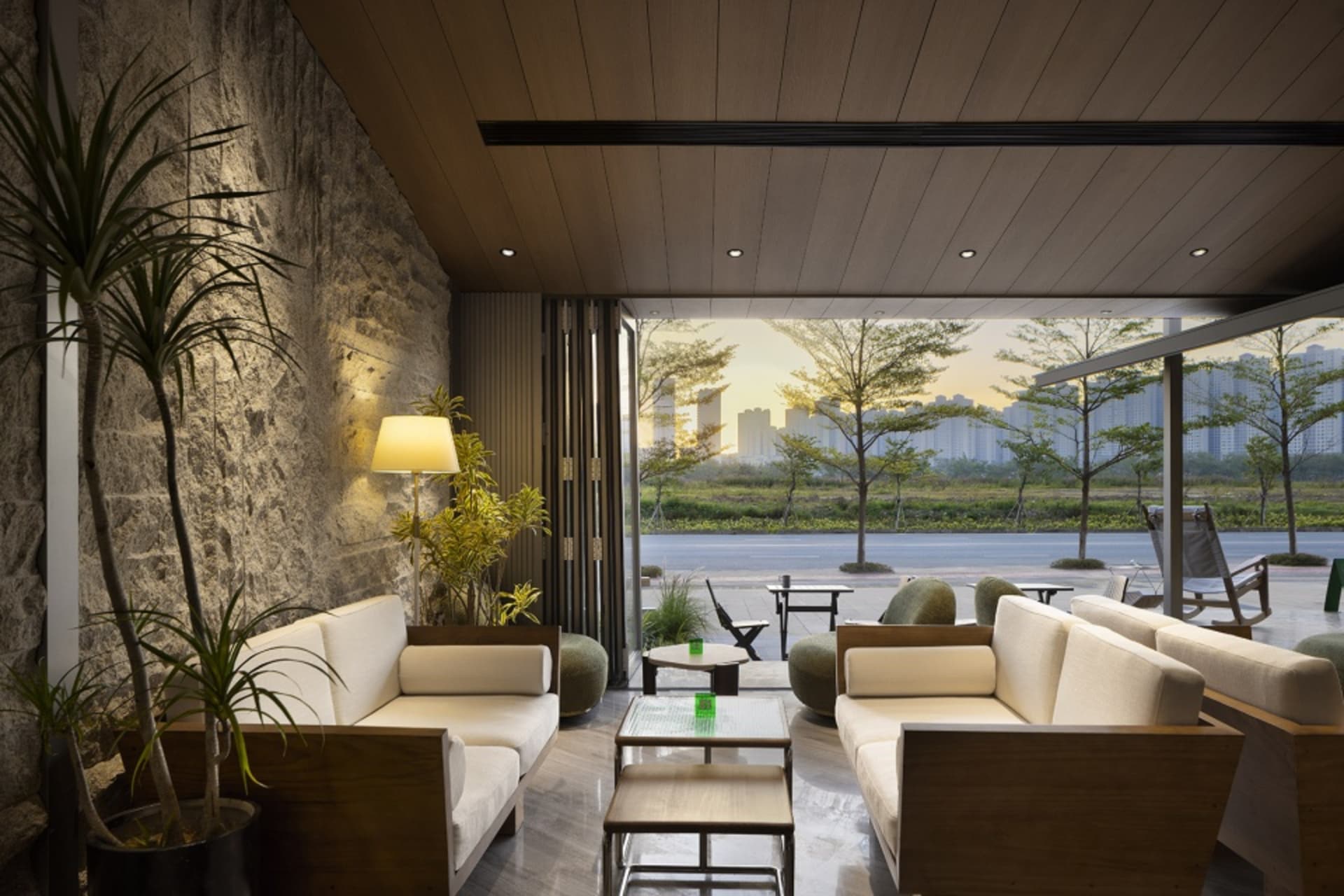Modern living room with white couches, wooden floors, and natural light from a large window
