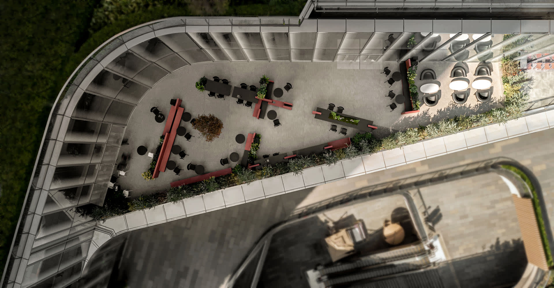 A rooftop space with multiple dining tables, potted plants, and wooden furniture, creating an inviting atmosphere for relaxation and socializing