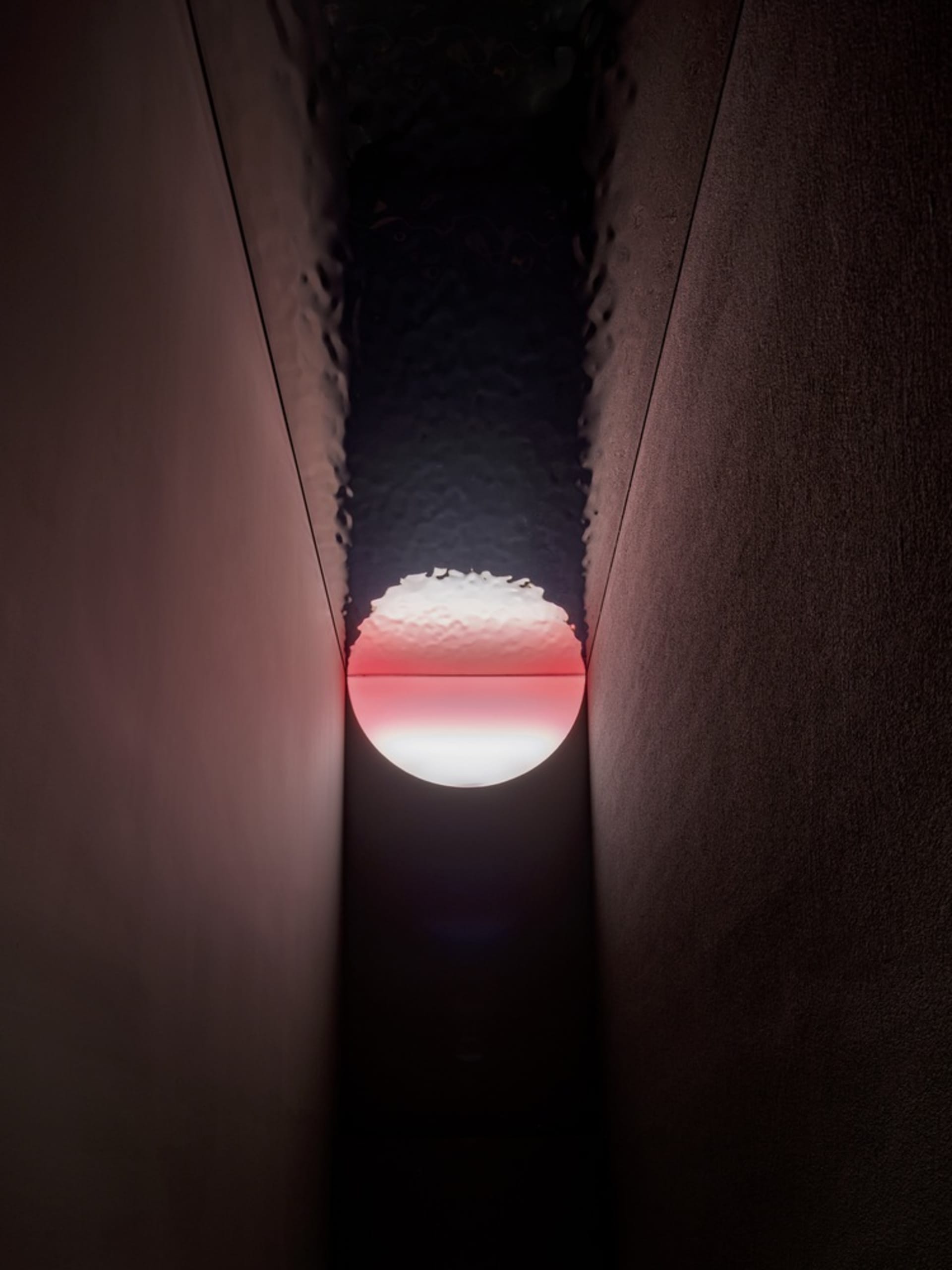 A darkened room with a small window showing a rising sun, creating a striking visual effect