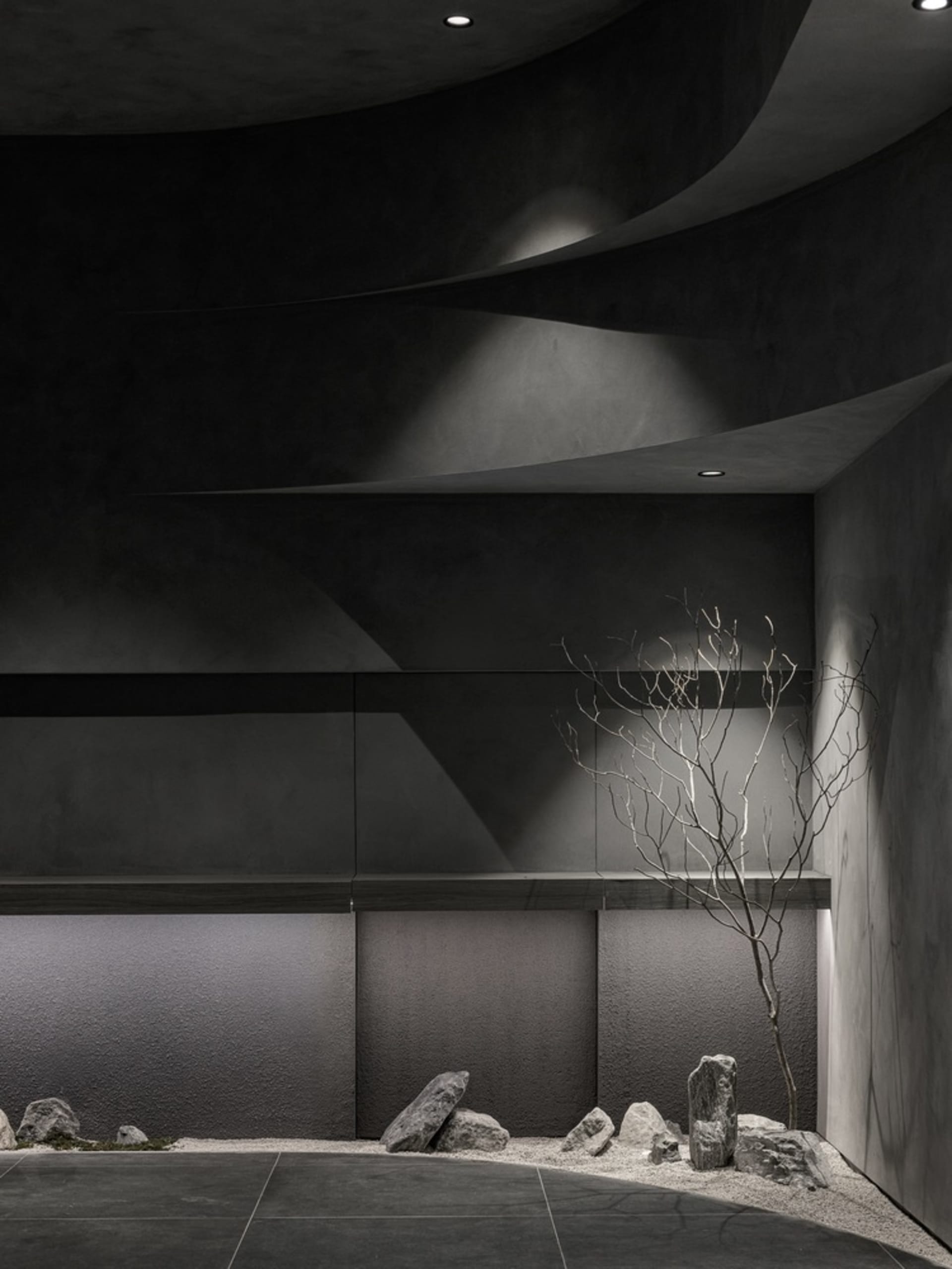 A dark room with a tree branch as its central feature, surrounded by a couch and dining table, with birds perched on the branch