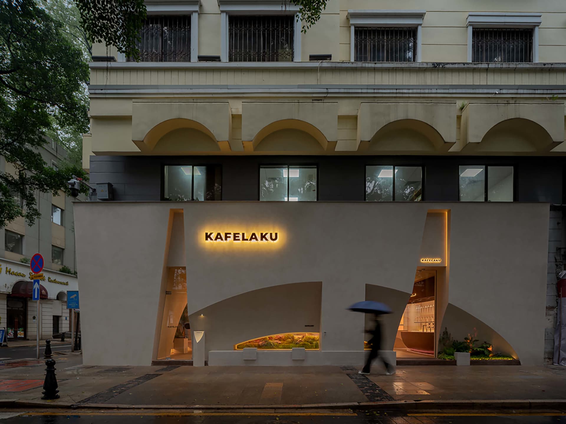 A modern city street scene with a large white building featuring a prominent archway, surrounded by urban elements and a potted plant