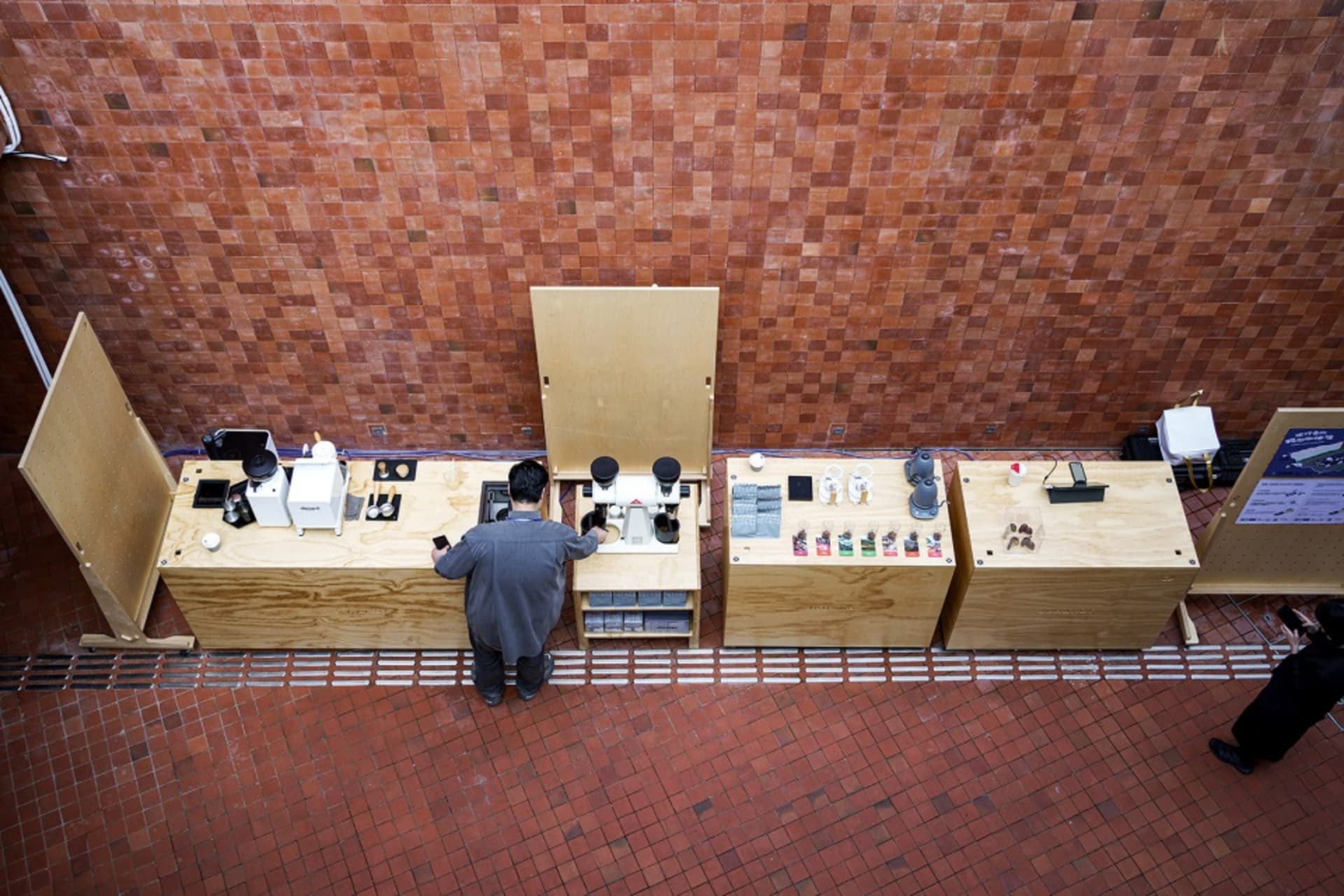 A casual indoor space with a brick wall, a wooden countertop, and various objects and people arranged in a relaxed atmosphere