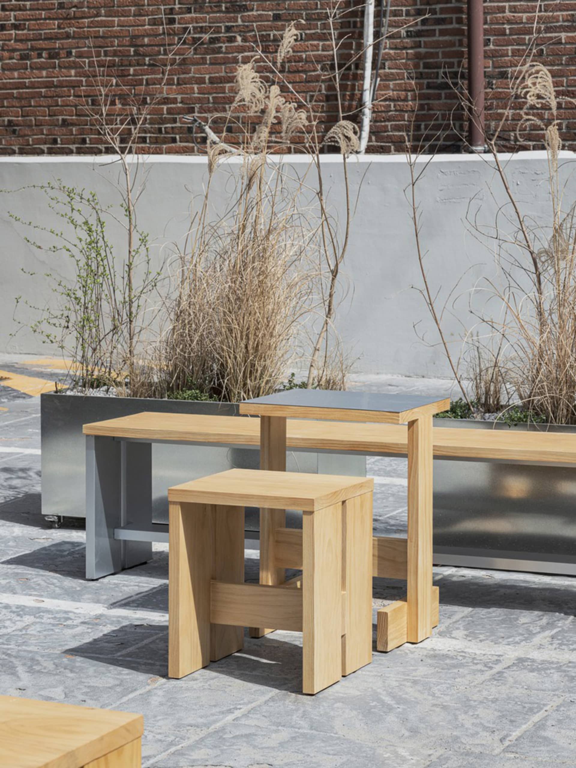 A relaxed outdoor patio area with two wooden benches, potted plants, and a concrete surface