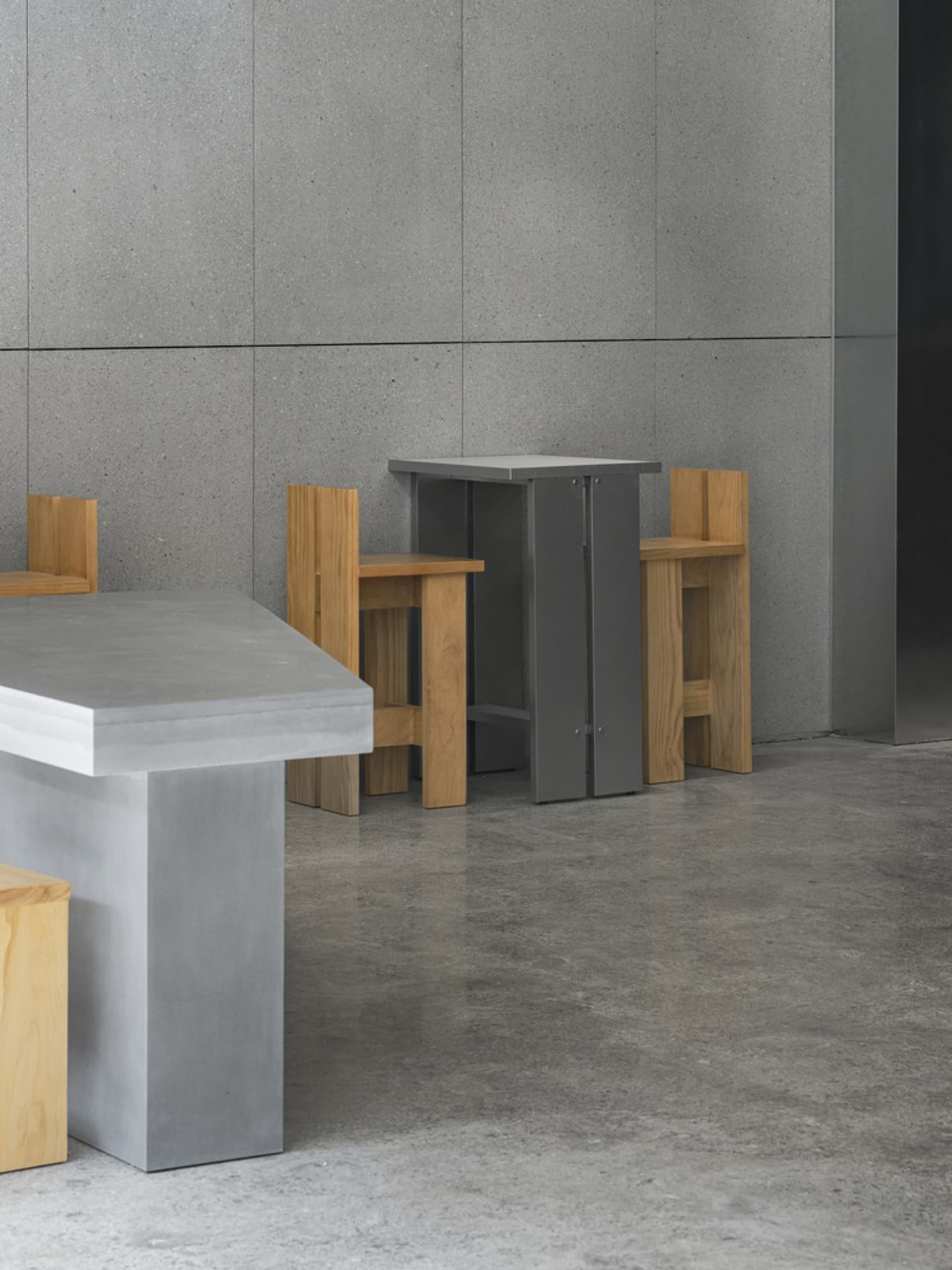Empty restaurant with grey walls and floors, wooden chairs, and dining tables, with a clean and well-organized atmosphere