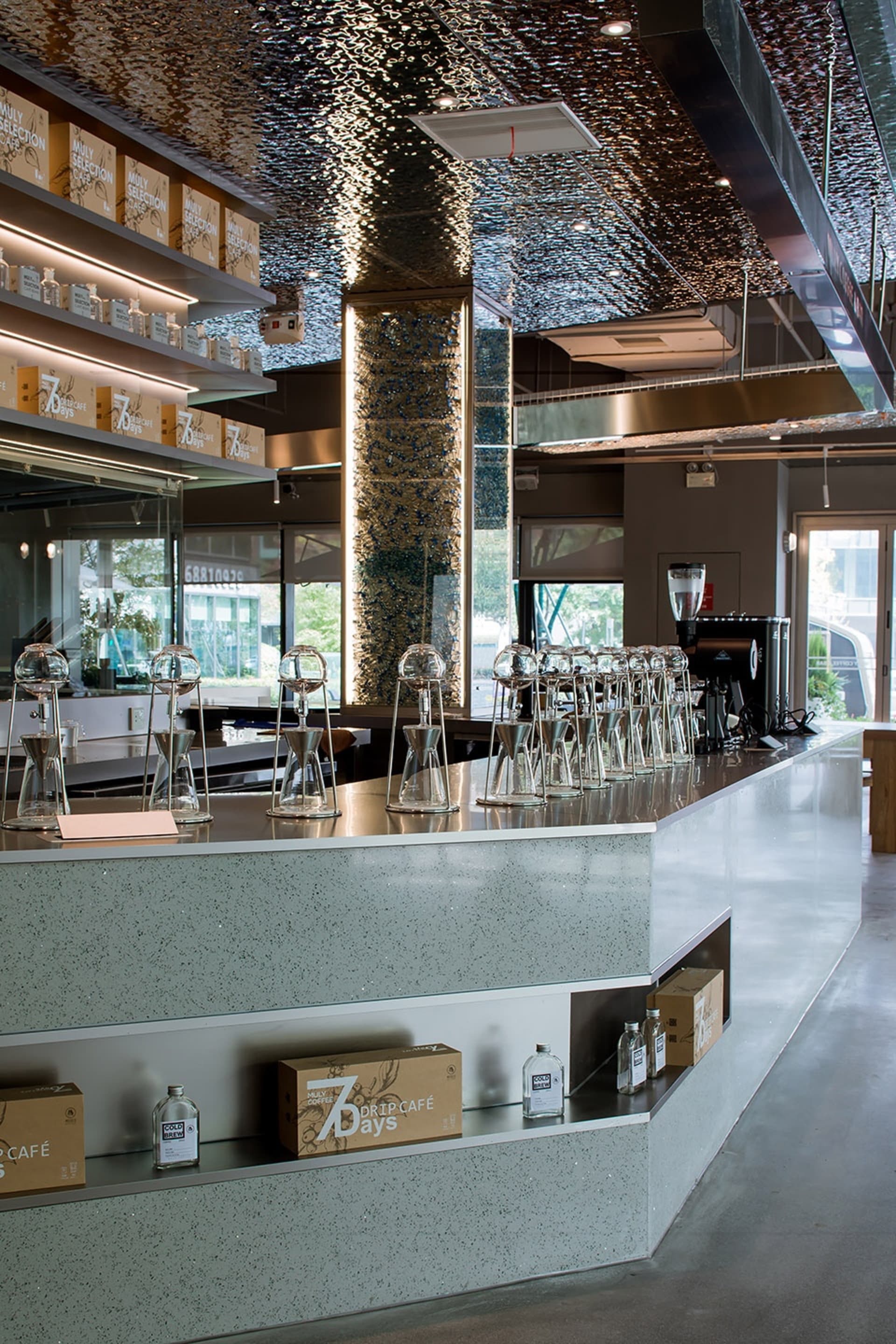 A modern restaurant counter with wine glasses, sleek surfaces, and minimalistic decorations