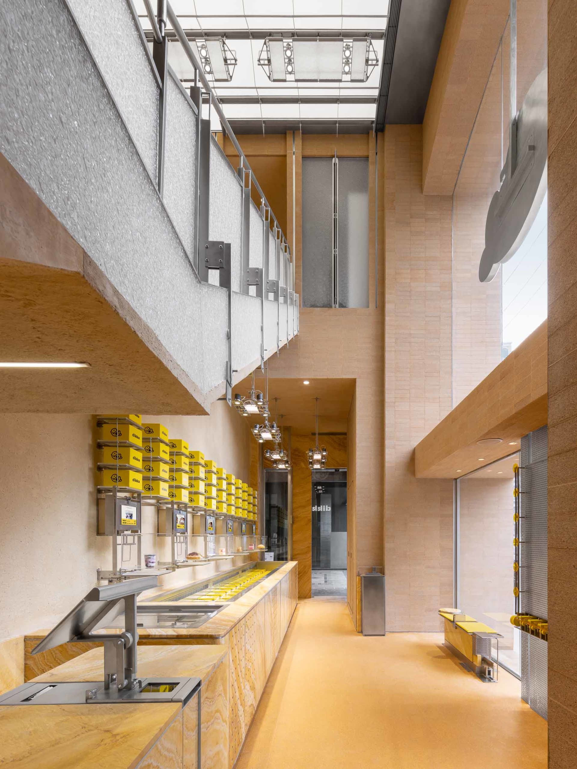Open commercial space with a counter, staircase, and yellow containers, suggesting a modern and functional design
