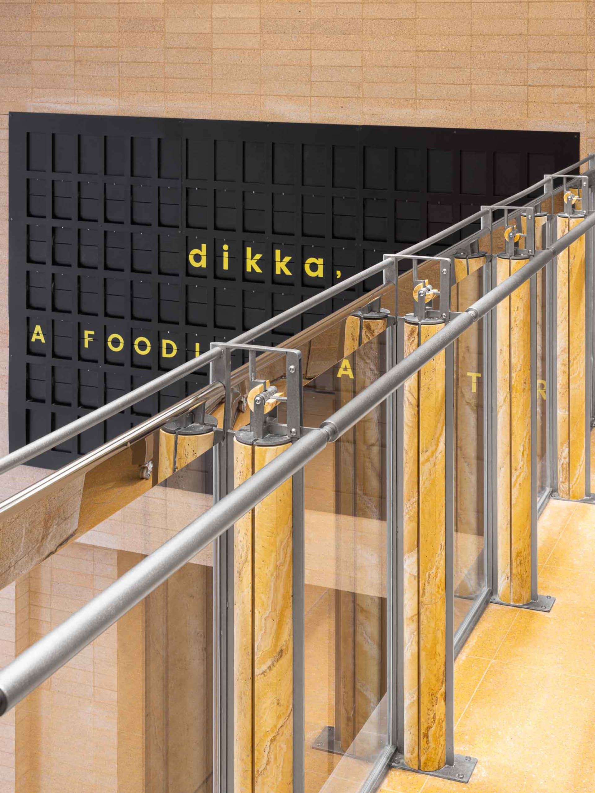Modern office space with a yellow accent wall, black lettering, and natural light from windows with curtains
