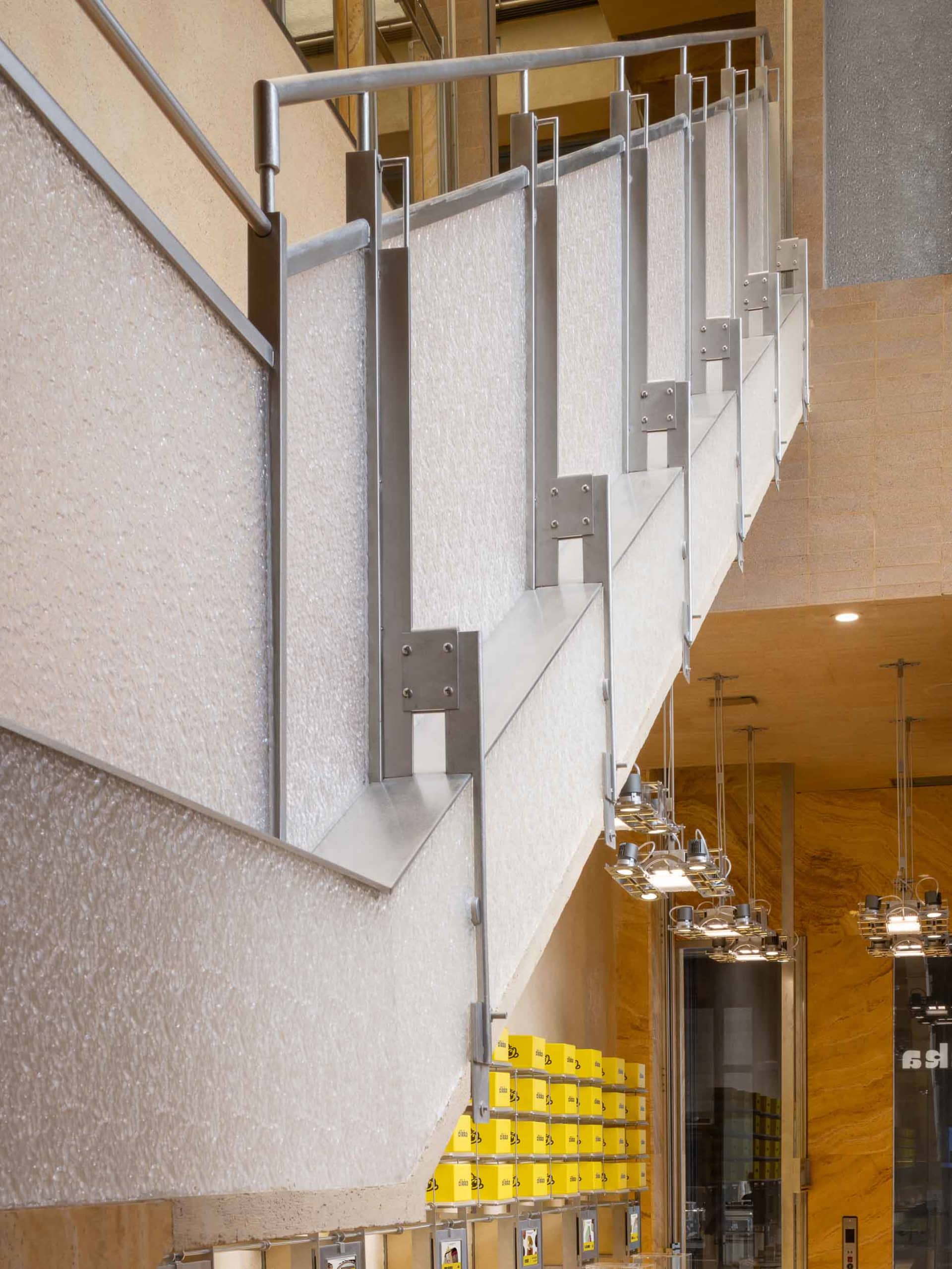 A well-lit staircase in a hotel with wooden steps and metal railings, illuminated by several lights along the stairwell