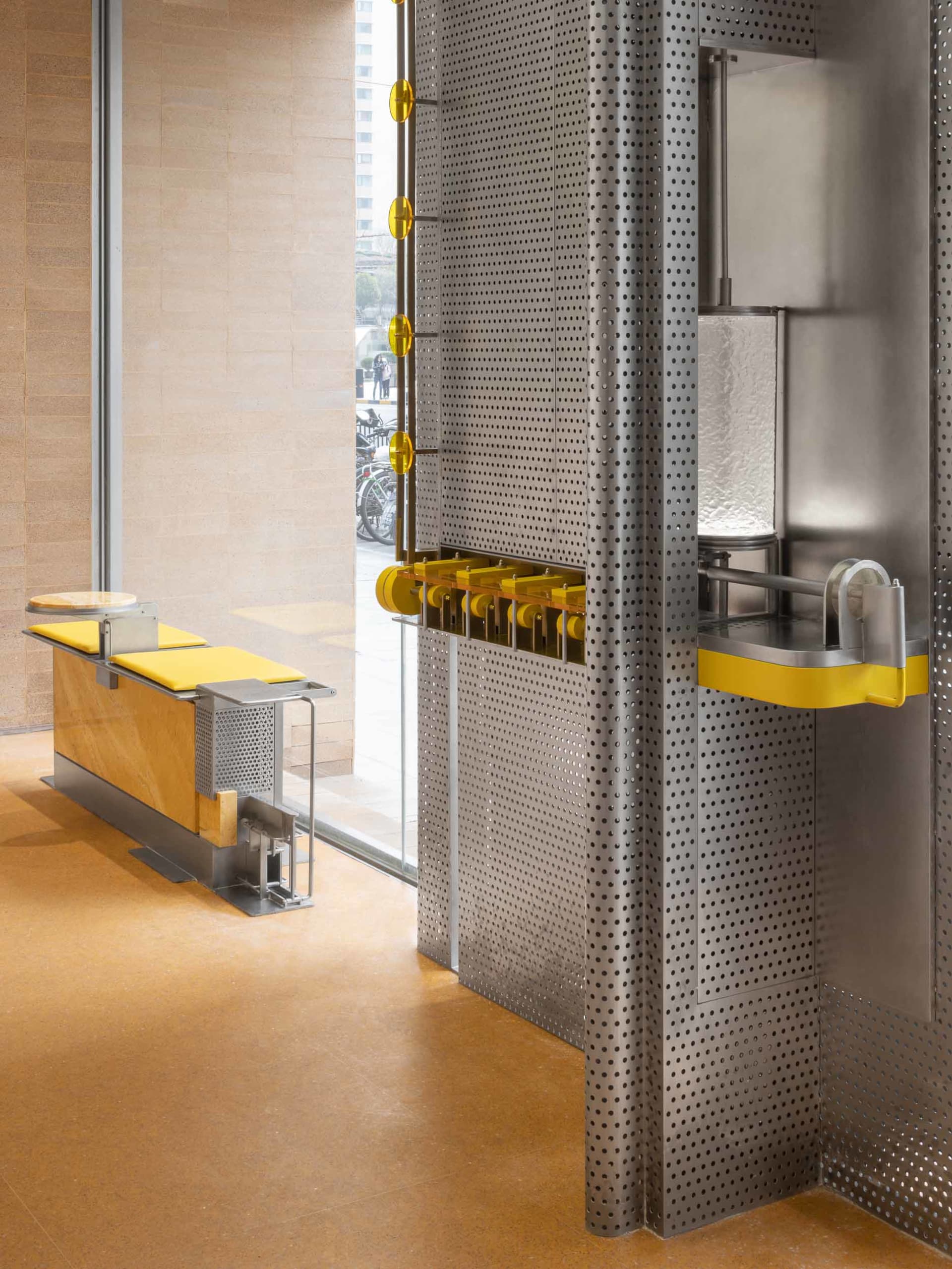 Industrial-style restaurant and bar space with metallic walls, dining tables, and benches, featuring a clock on the wall and a welcoming atmosphere