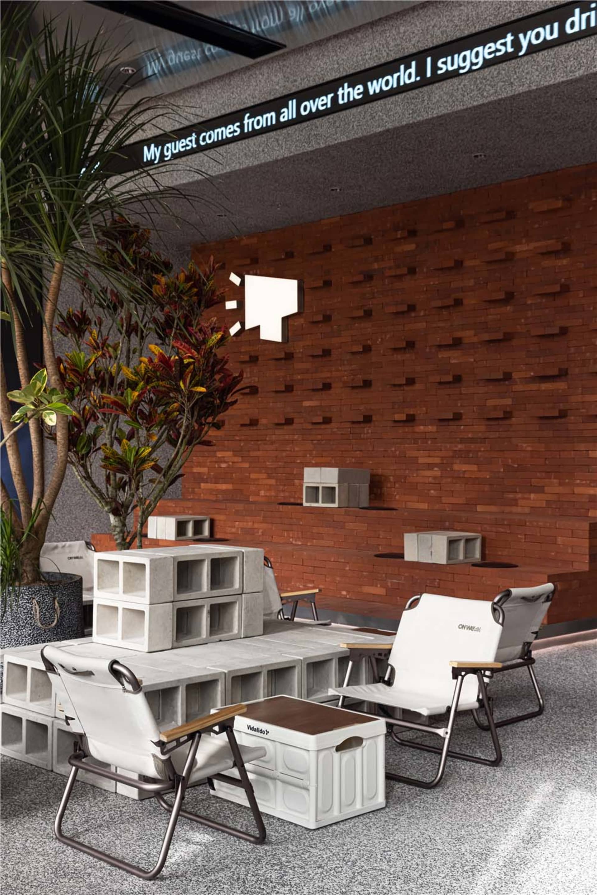Cozy room with a brick wall, a large tree, two chairs, and a dining table