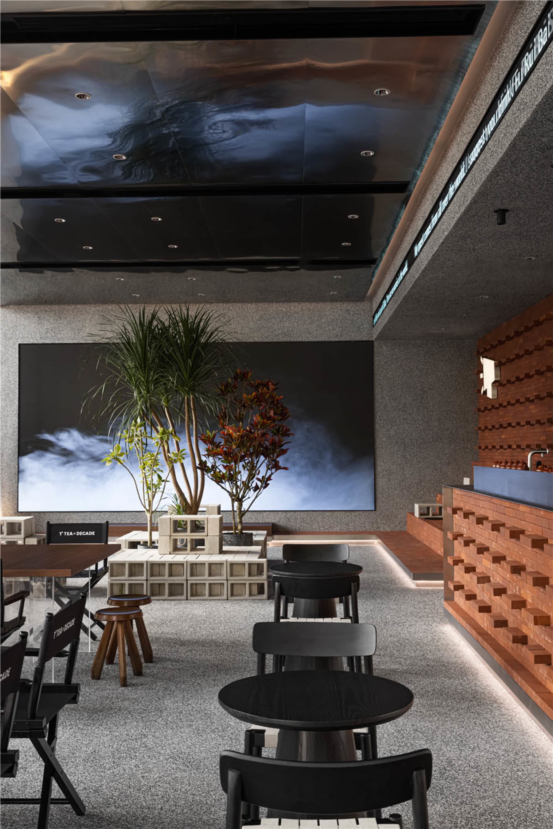 Gray walls and wooden elements create a warm atmosphere in this modern cafe with seating areas and potted plants