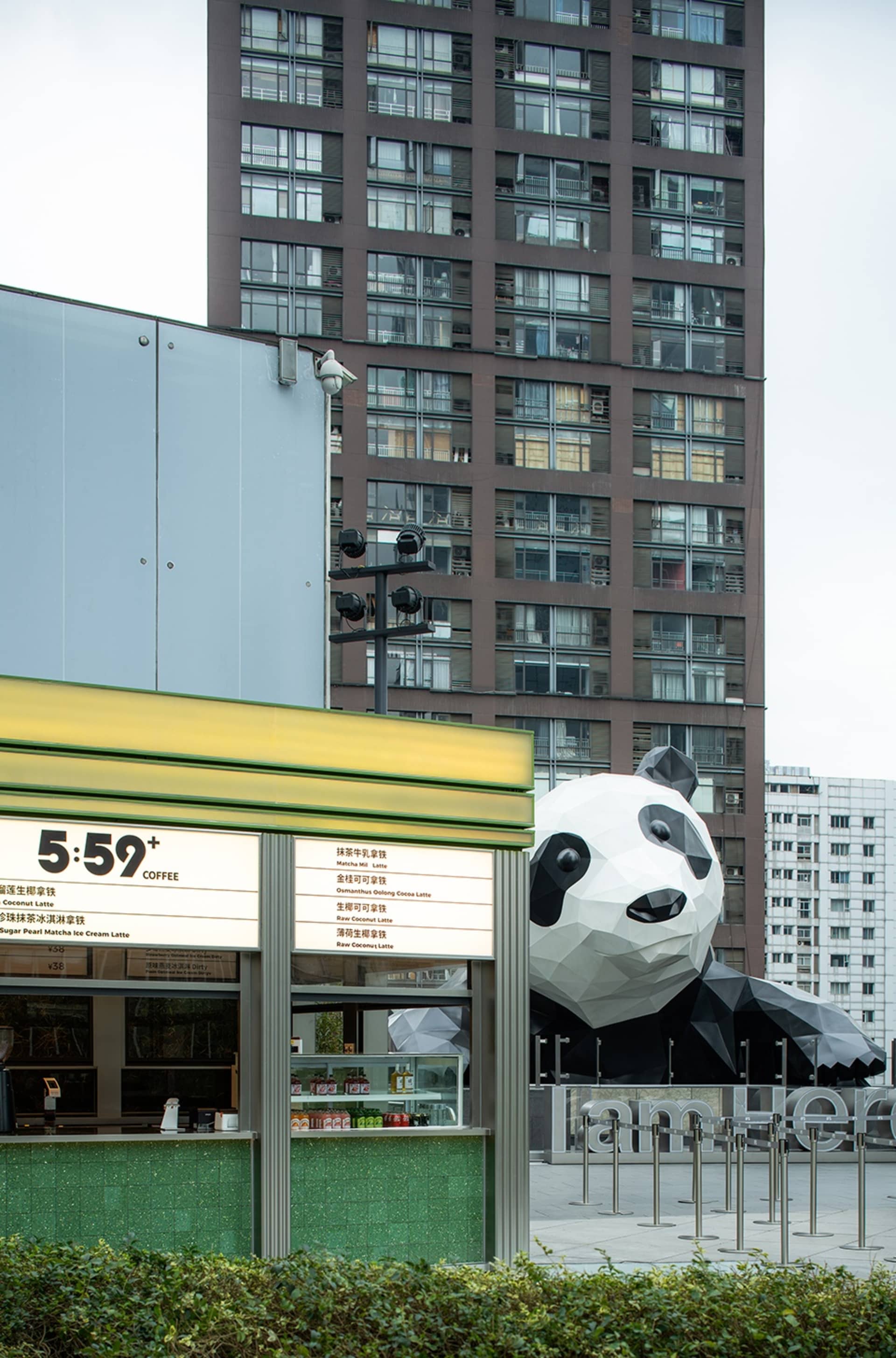 A modern building with a large concrete panda statue in front, set against a urban backdrop
