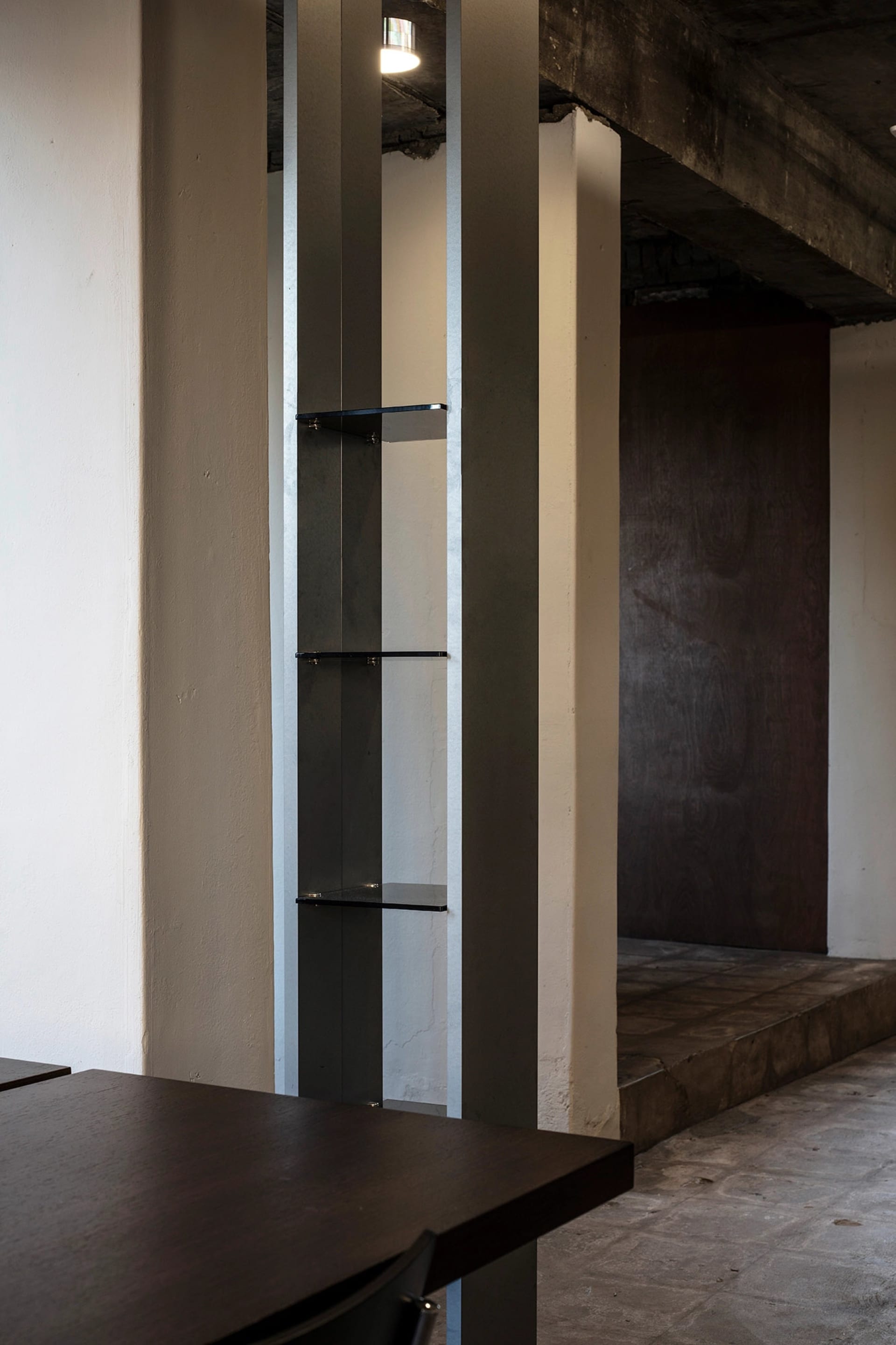 A well-lit interior space with a metal bookshelf mounted on a wall, filled with books of varying sizes and orientations