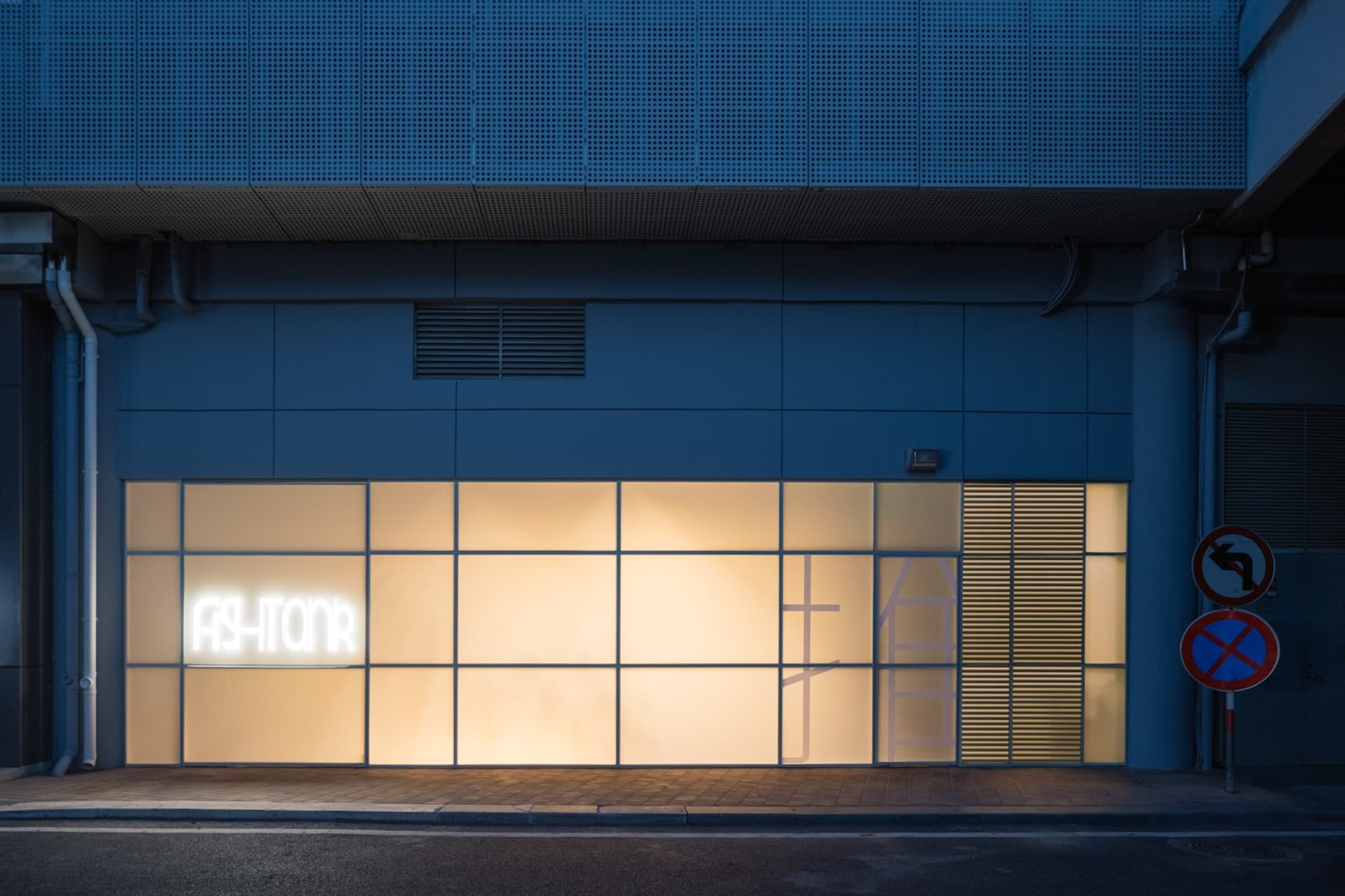 A modern storefront with a large window lit up by neon lights, showcasing a clean and minimalist design