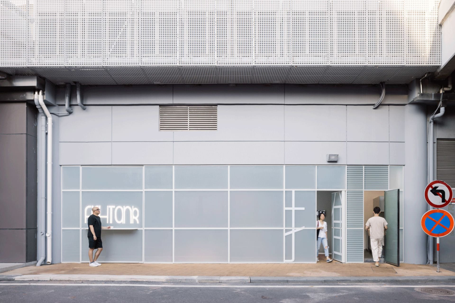 Casual street scene with people looking at a building with a large window that says PHIONR