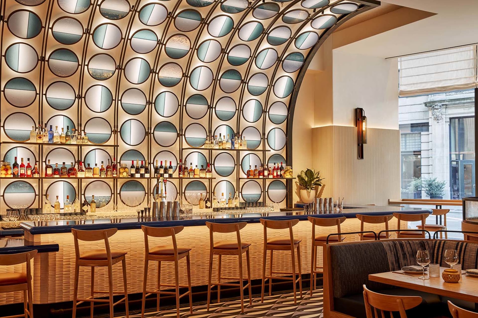 A modern bar area with a long counter and multiple chairs, featuring bottles and a sophisticated atmosphere