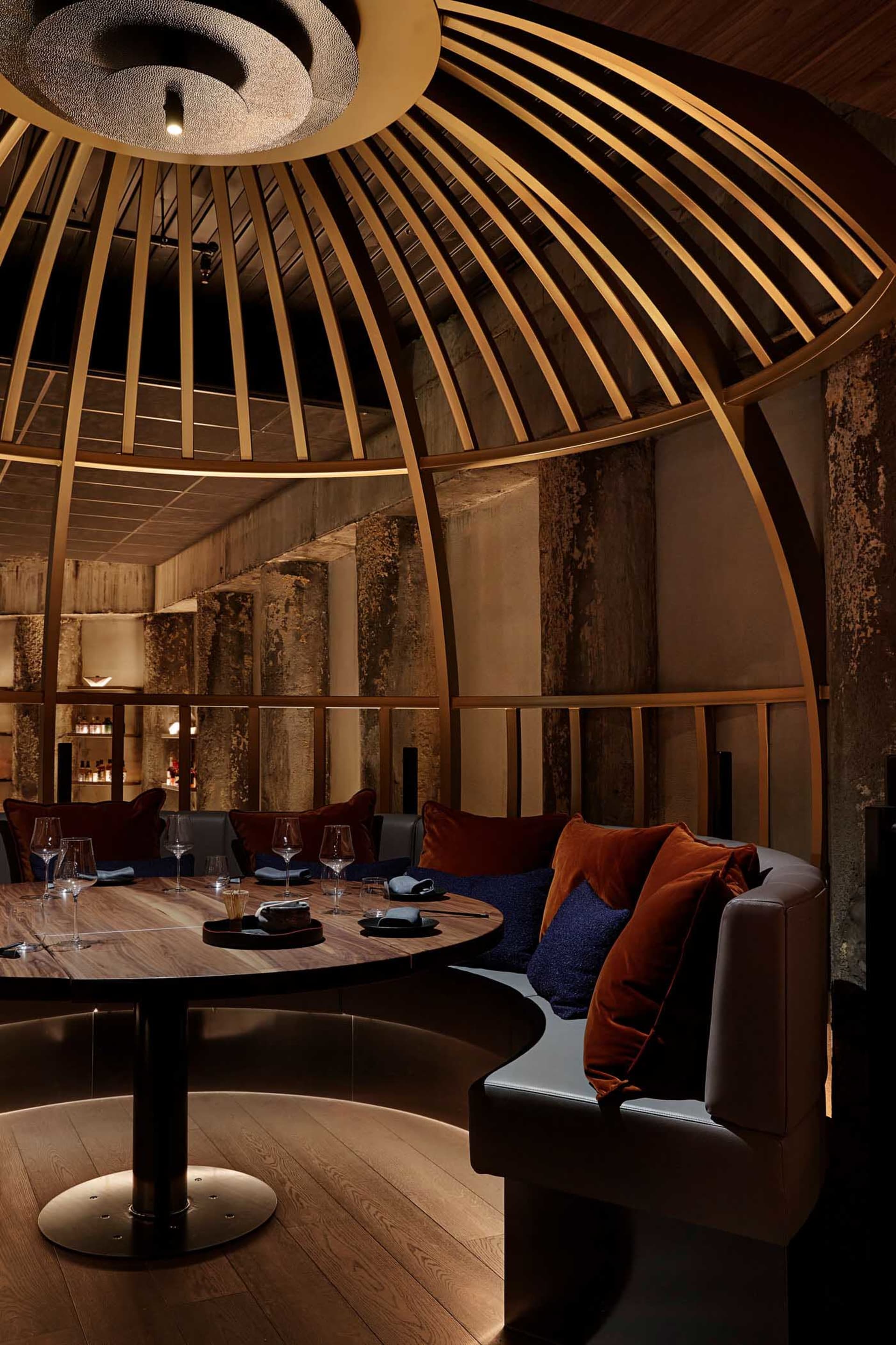 A modern dining area with a circular table, wine glasses, and couches, creating a sophisticated ambiance
