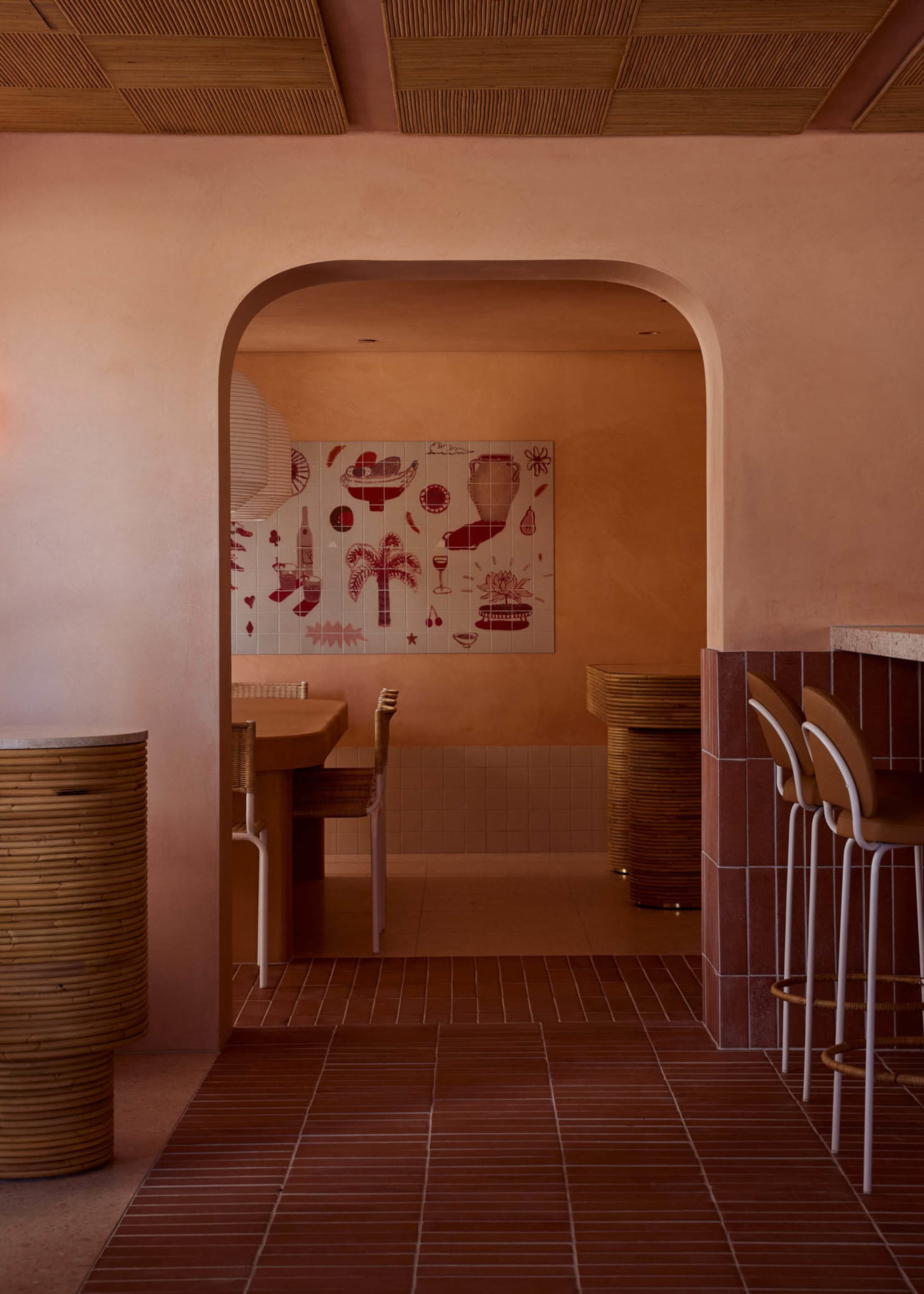 A modern restaurant with a dining area featuring three chairs and two tables, surrounded by pink walls and a warm atmosphere