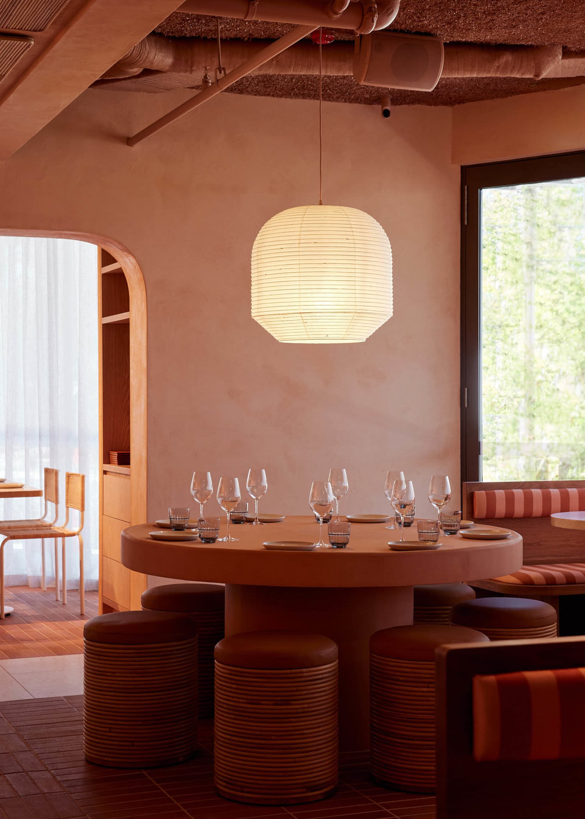 Warm and inviting restaurant interior with a round table, chairs, and wood elements, featuring wine glasses and a cozy atmosphere