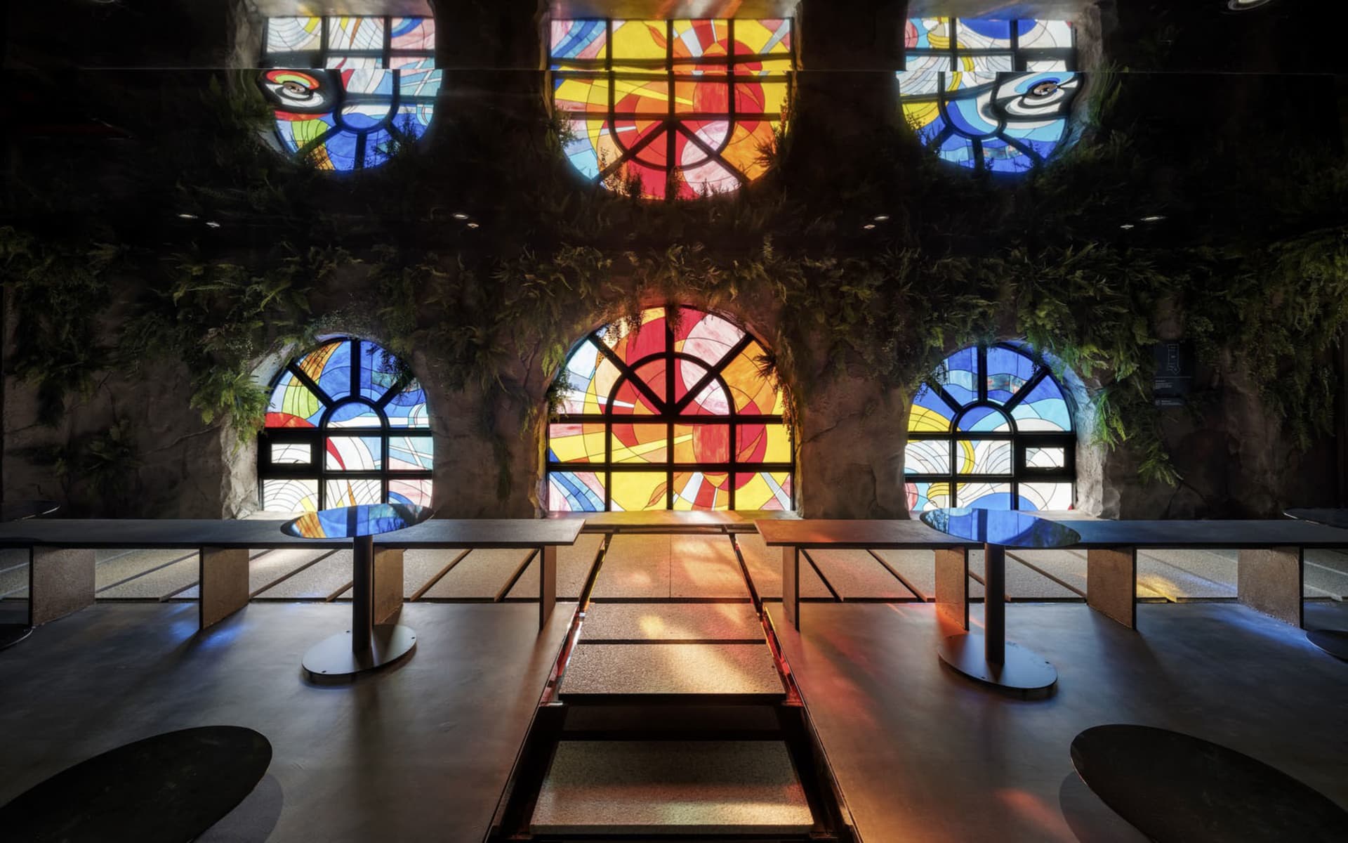 Warm and inviting cafe space with stained glass window, multiple tables, and natural light