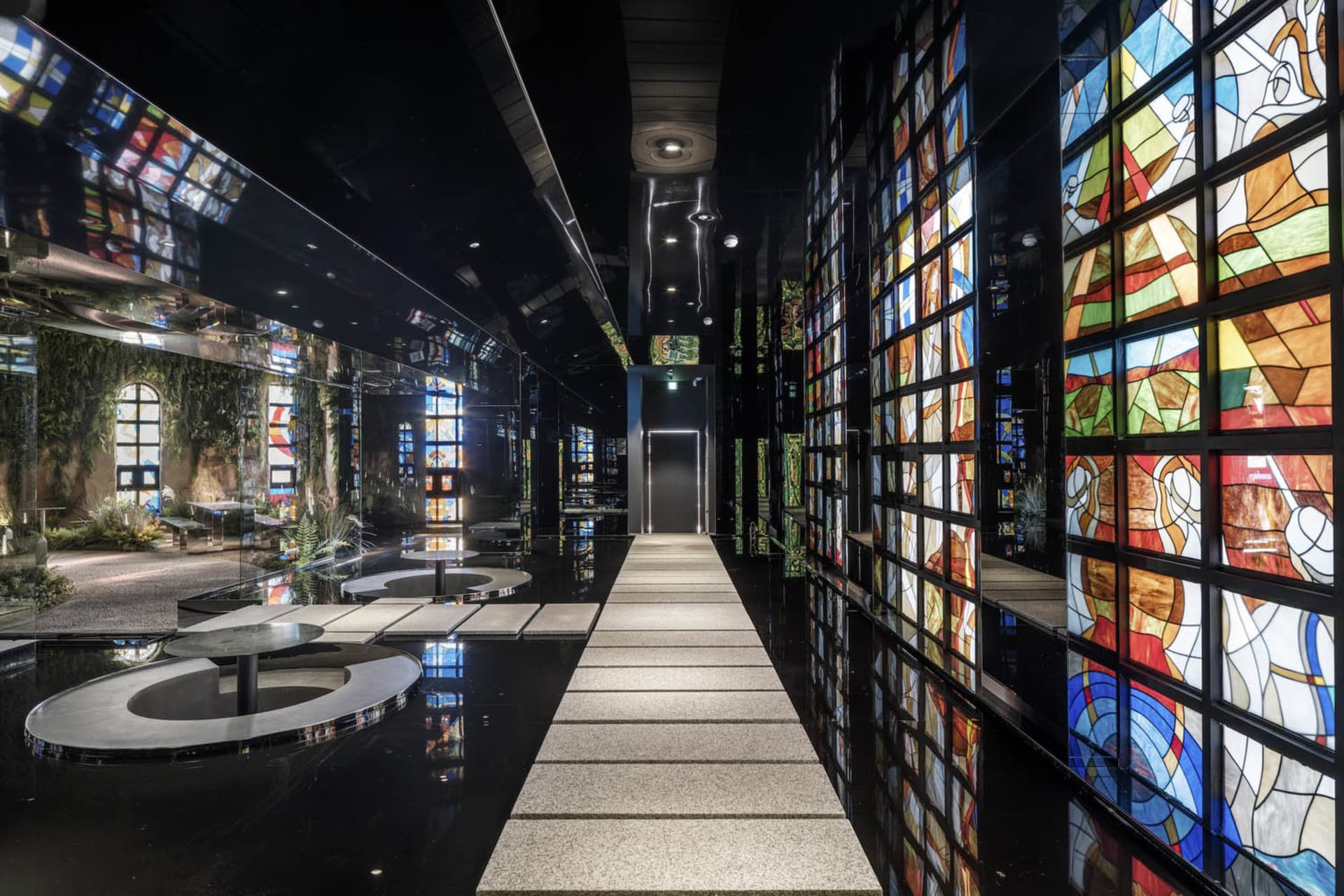 A museum-style hallway with stained glass windows, patterned walls, and benches, creating a unique and artistic atmosphere